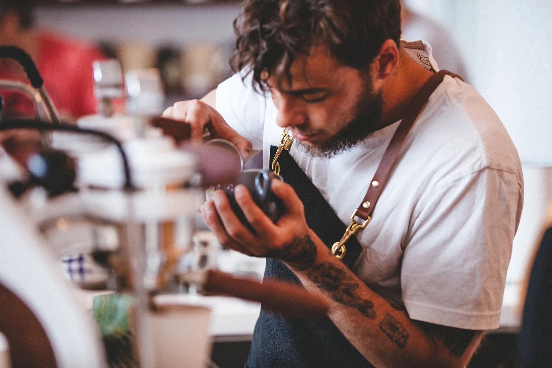 Close-up of a barista examining a coffee cup in a coffee shop.