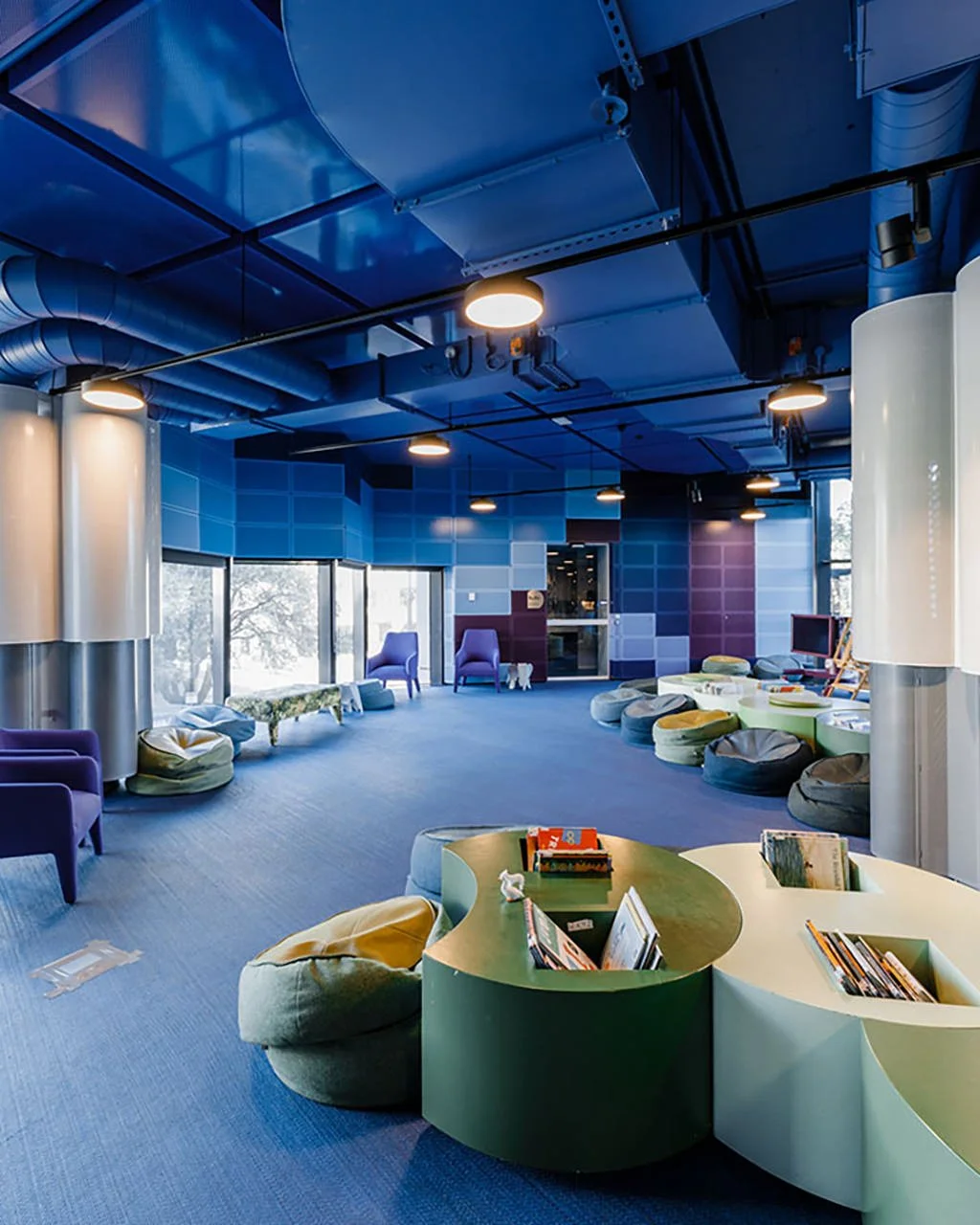 Colorful modern lounge area with bean bag chairs, seating, and a bookshelf with children's books.