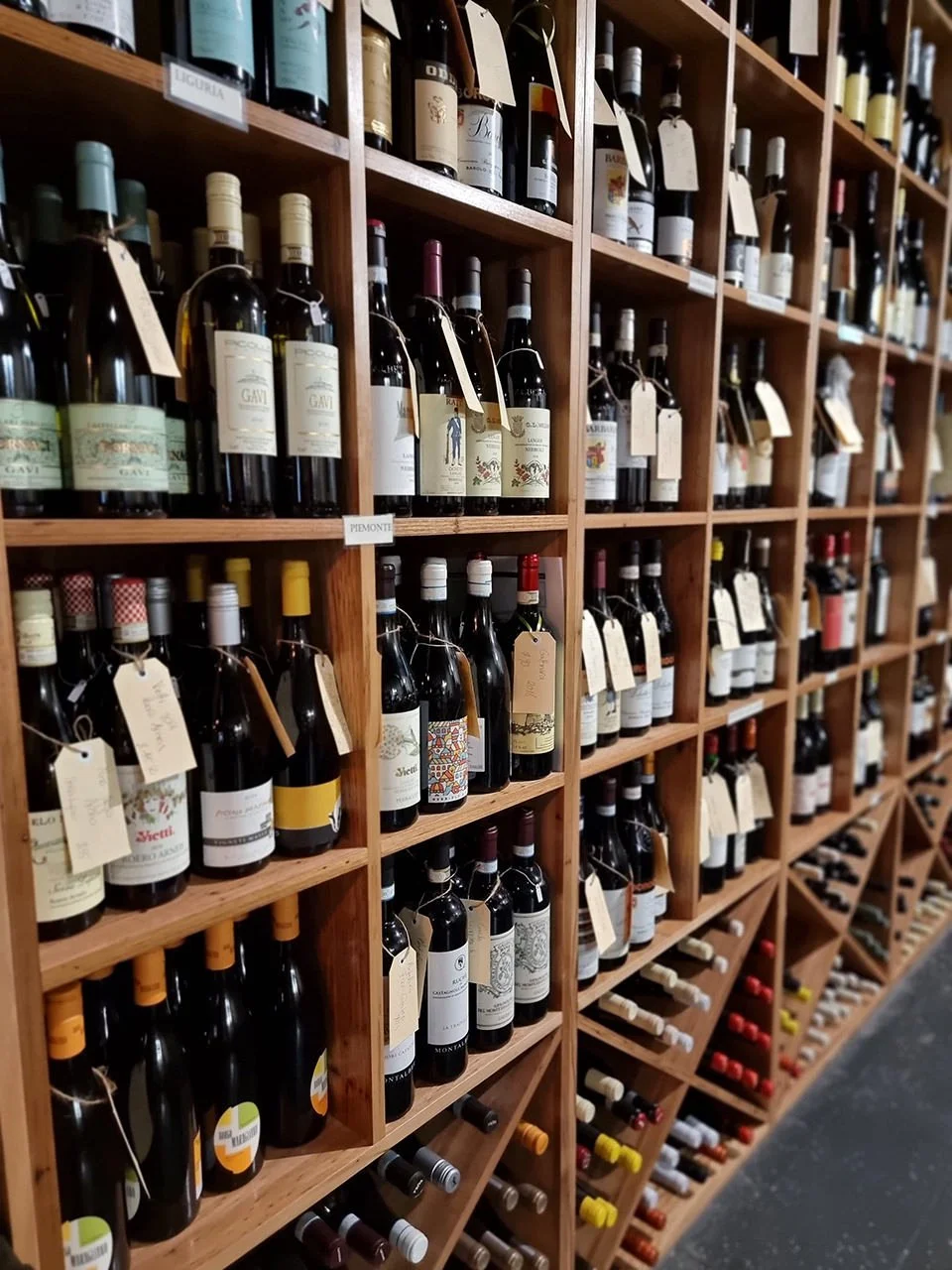 Several wooden shelves filled with wine bottles in a wine store.