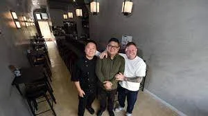 Three men standing together in a restaurant or cafe.