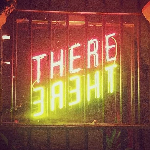 Neon sign that reads 'THERE' in red and 'CHEAT' in yellow, with the latter appearing reversed.