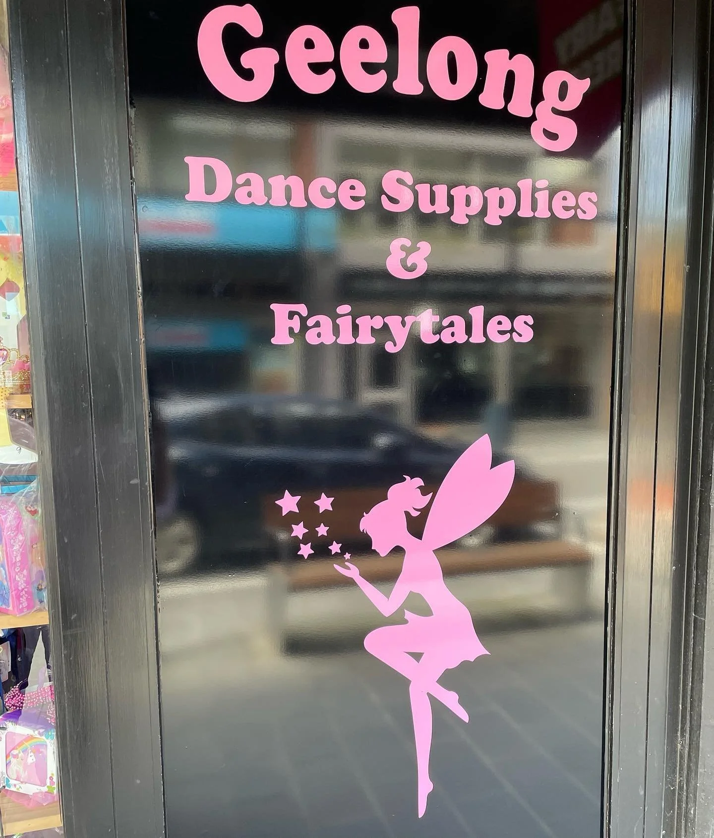 Sign on door for Geelong Dance Supplies & Fairytales with a pink fairy silhouette sitting and blowing stars.