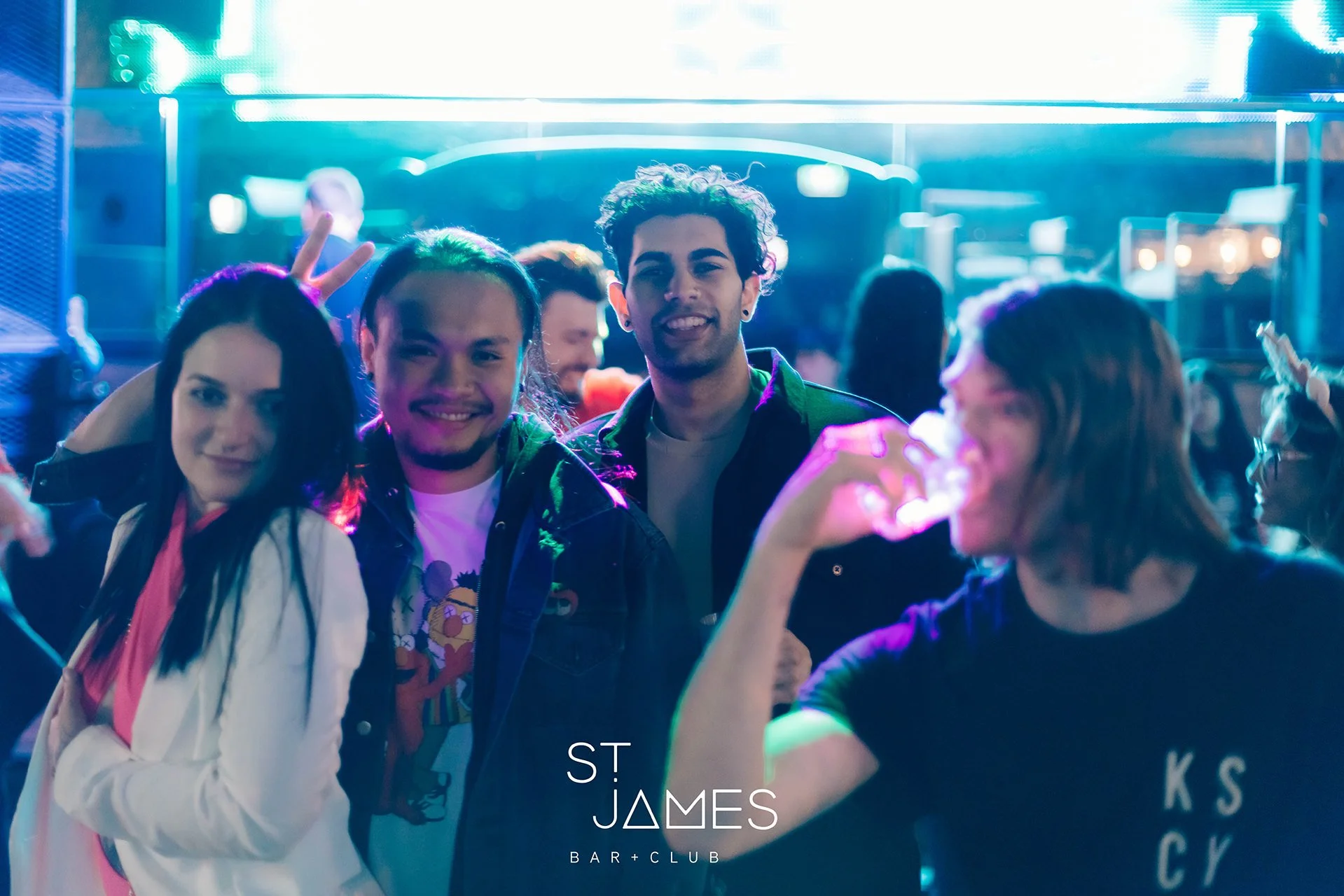 Group of young friends enjoying a night out at a bar and club, with colorful neon lights, smiling and socializing.