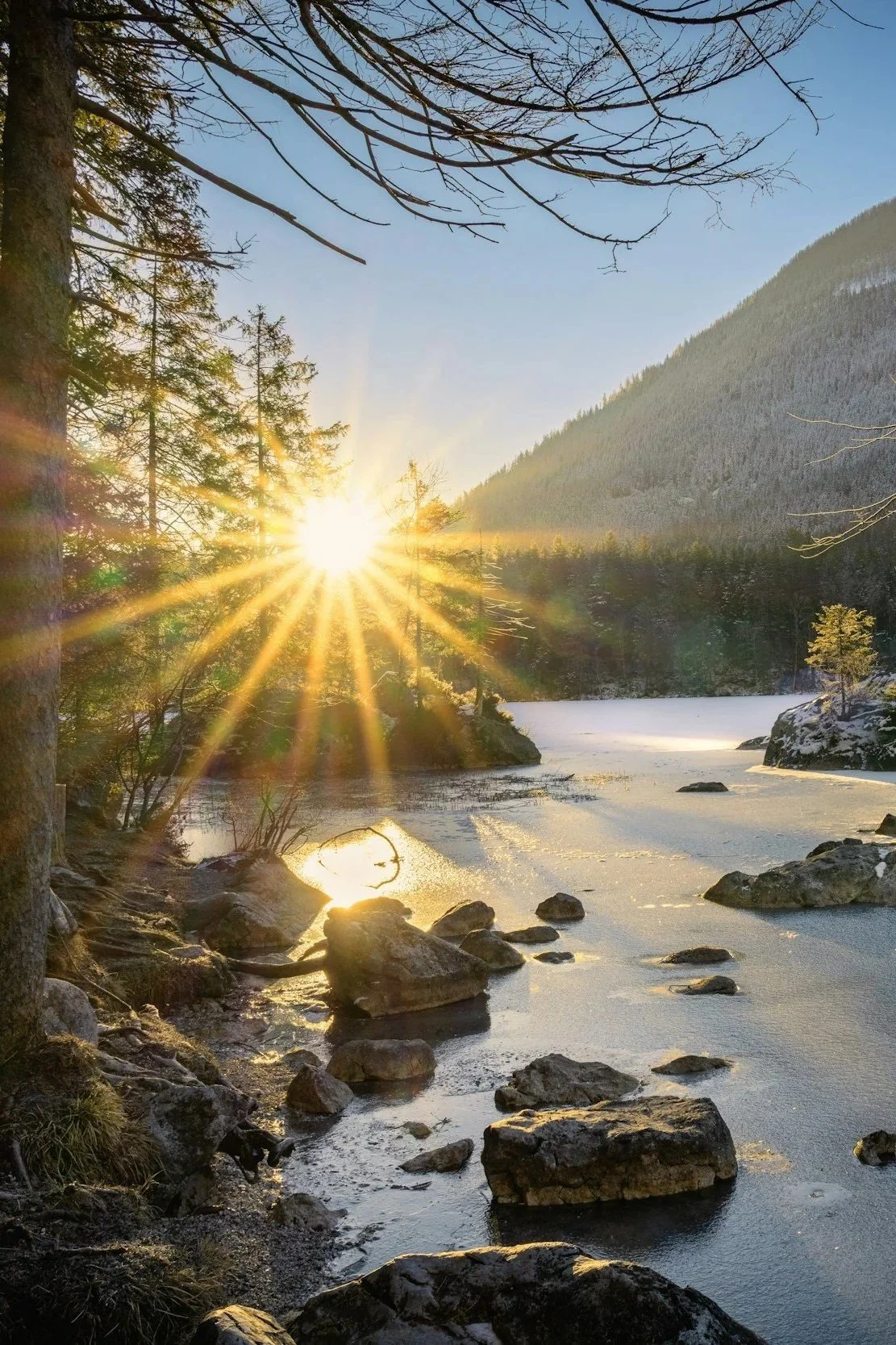 Sunset over a river in a snowy mountainous forest