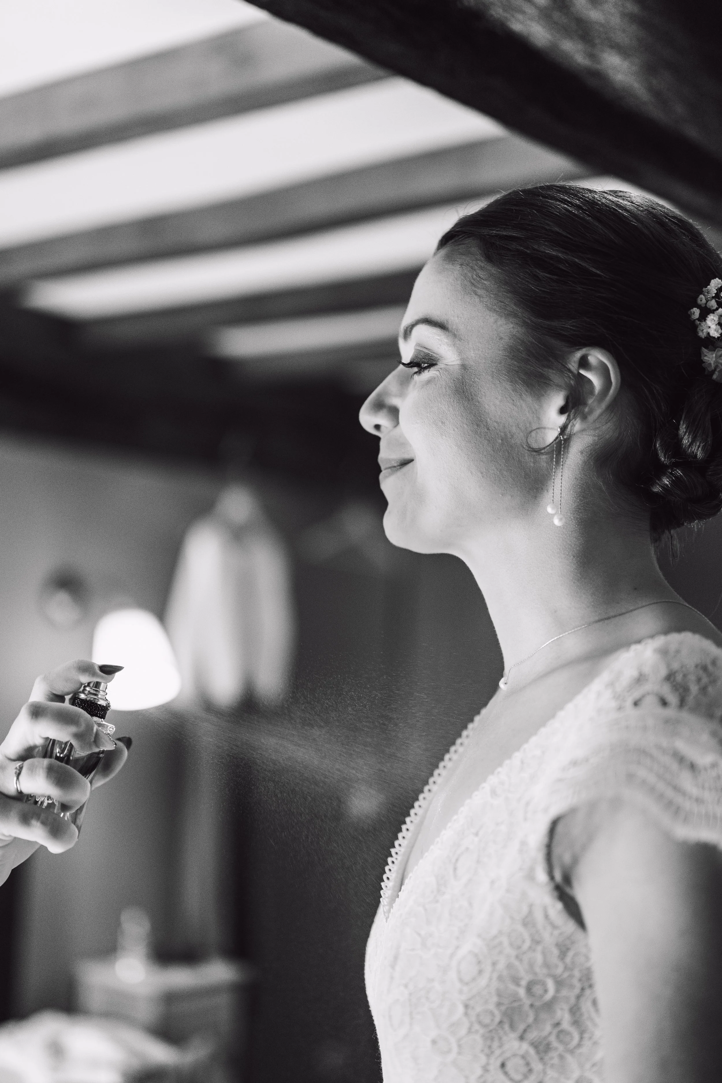 Une femme portant une robe de mariée est aspergée de parfum, en noir et blanc.