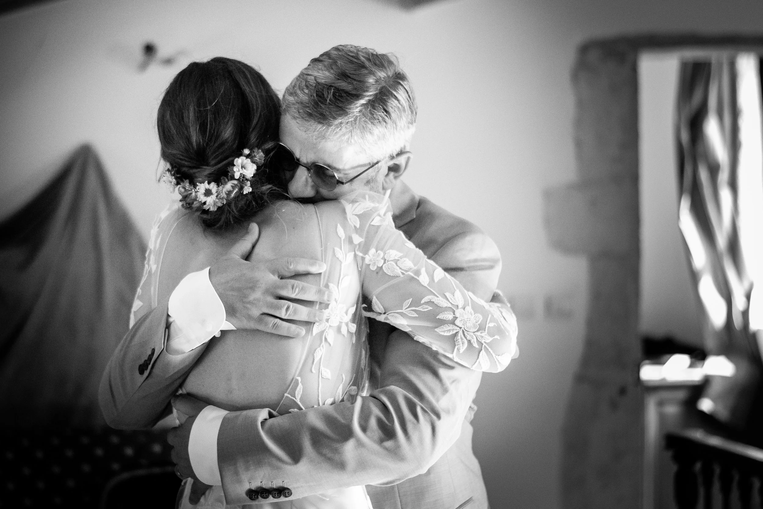 Une personne en costume et une femme avec une robe à broderie florale s'embrassent.