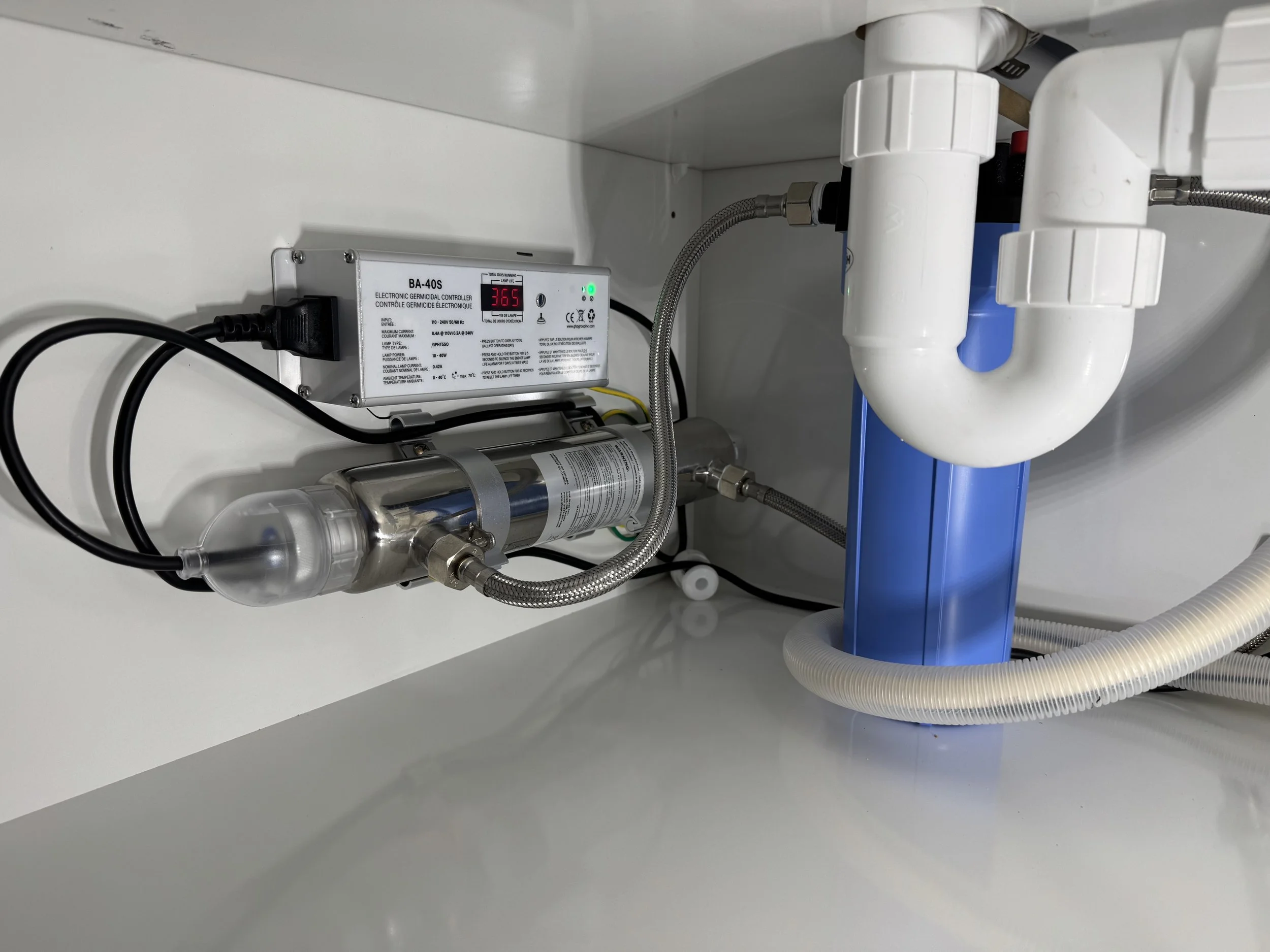 Undersink water filtration system with filtration unit, tubing, and electronic control box.