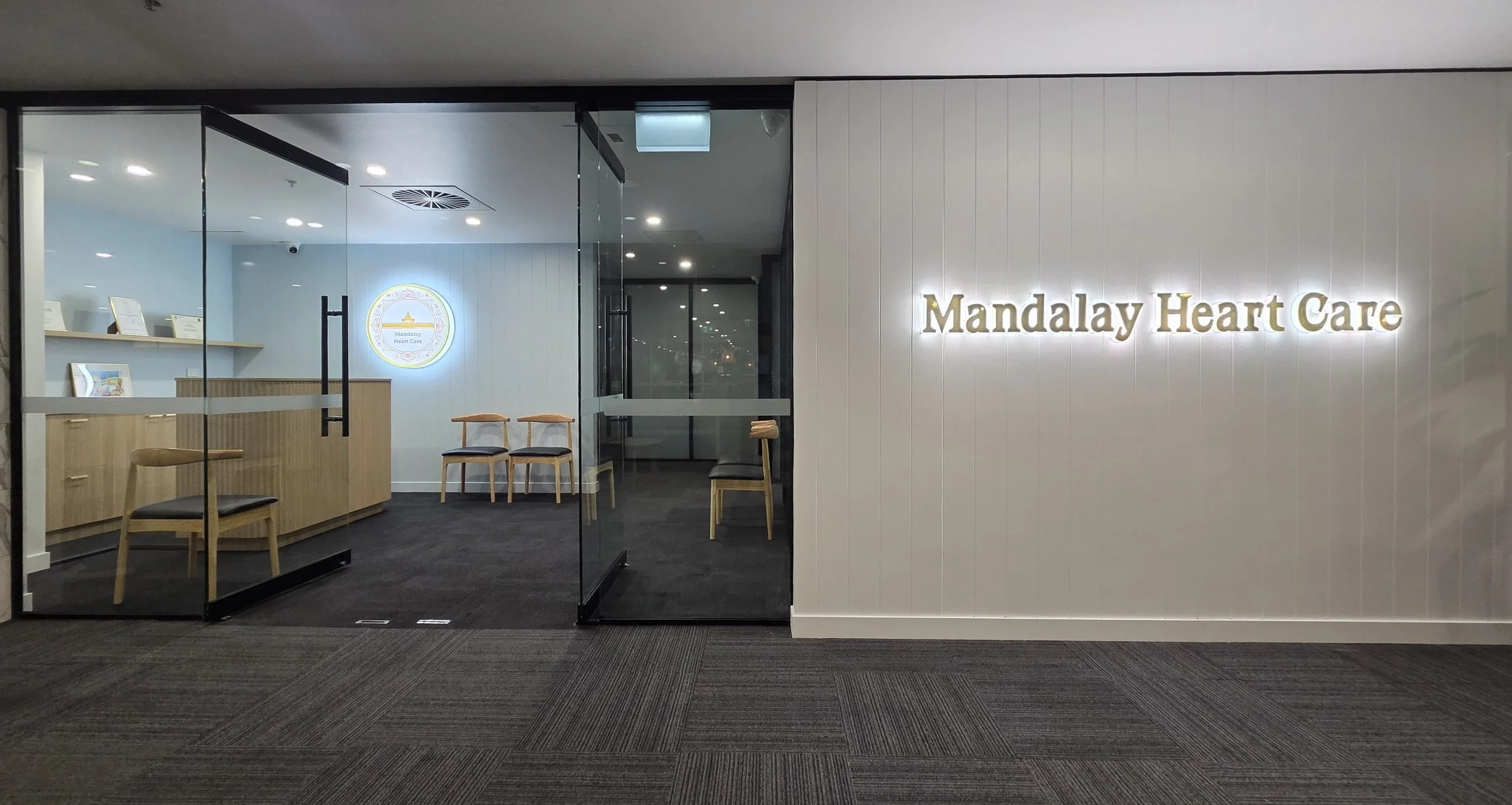 Interior view of Mandalay Heart Care, a medical clinic with a white wall, illuminated sign, reception desk with chairs, and modern decor.