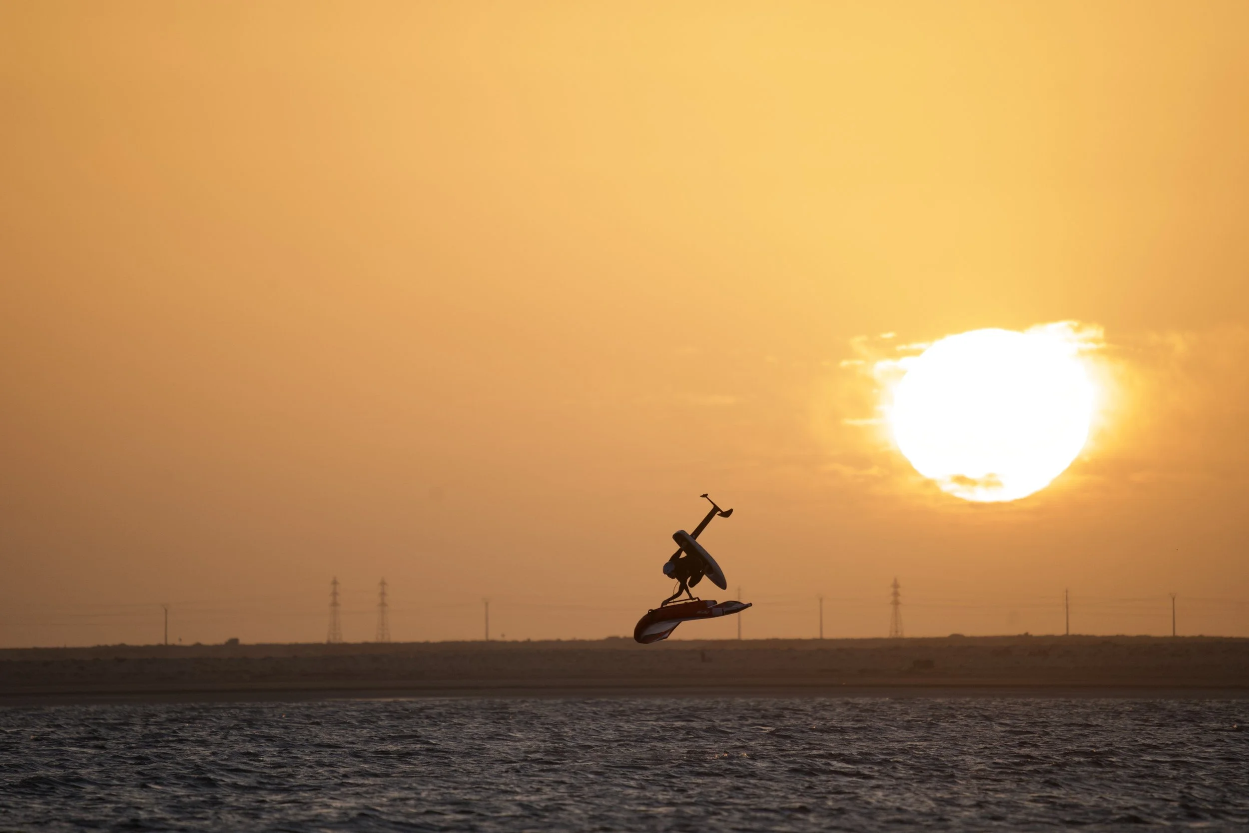 Axel Gerard en plein saut au-dessus de l'eau au coucher du soleil.