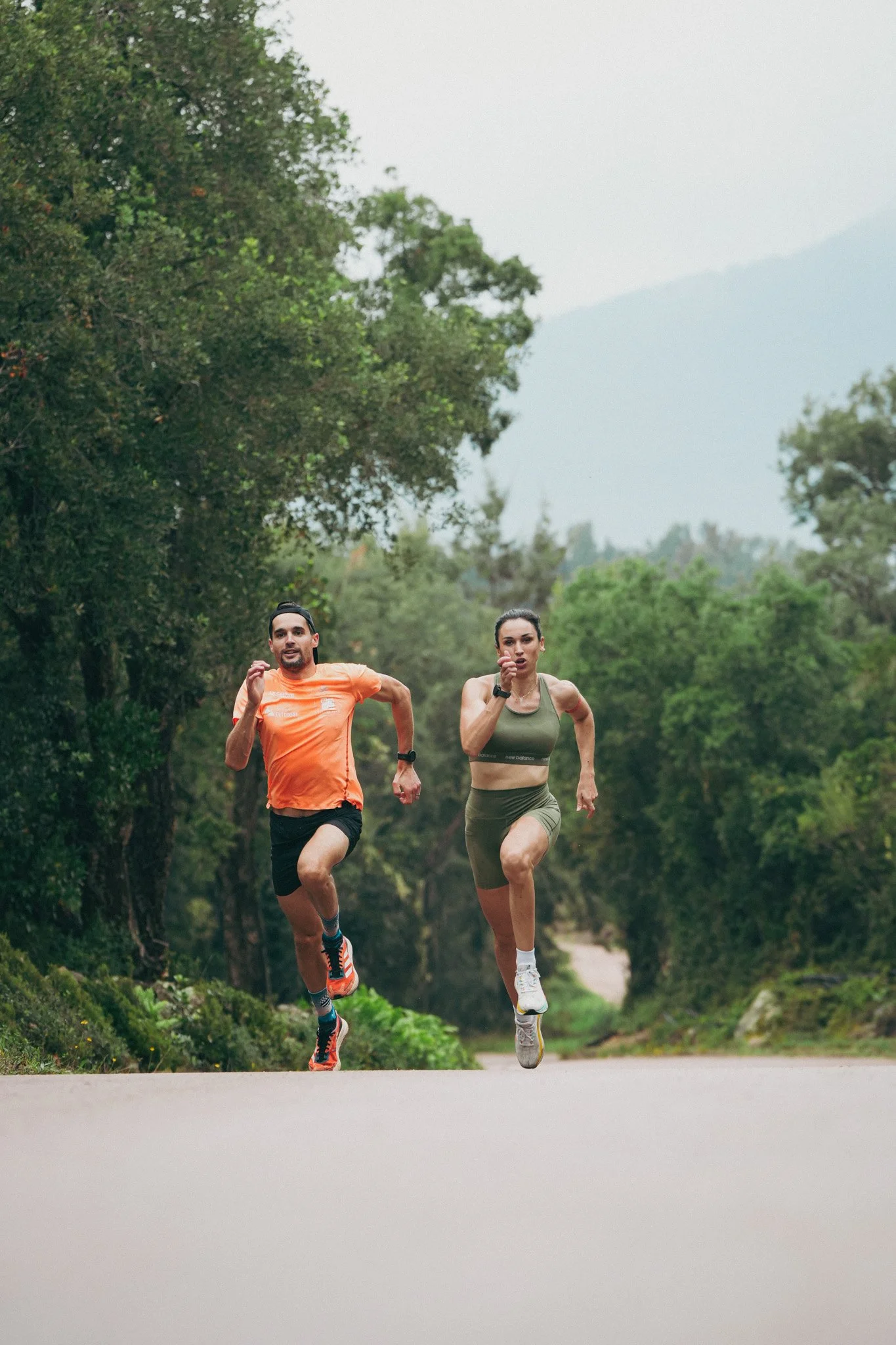 Deux personnes en tenue de sport courant sur un chemin dans la nature, entourées d'arbres et de verdure.