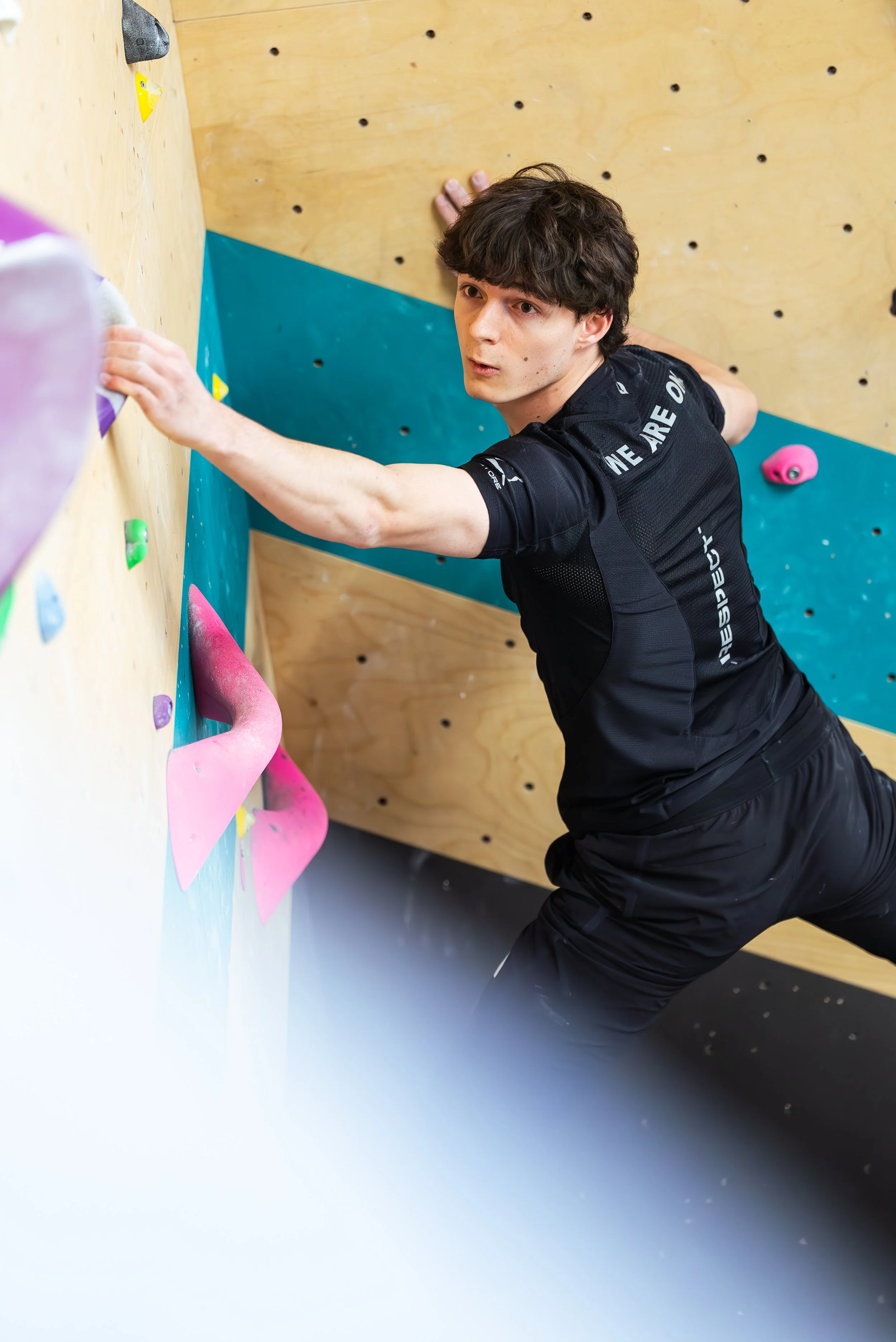 Gabriel cancel boulay en vêtements de sport grimpant sur un mur d'escalade intérieur, regardant vers l'objectif.