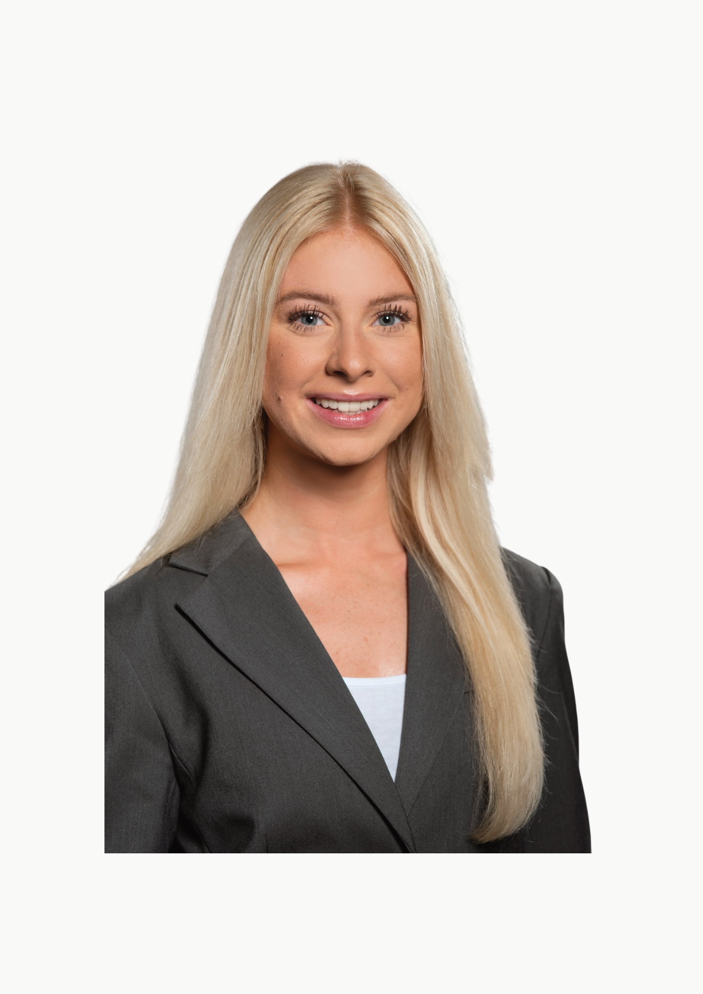 Porträt einer lächelnden jungen Frau mit langem blondem Haar, schwarzen Augen, in dunklem Blazer über weißem Top, vor weißem Hintergrund.