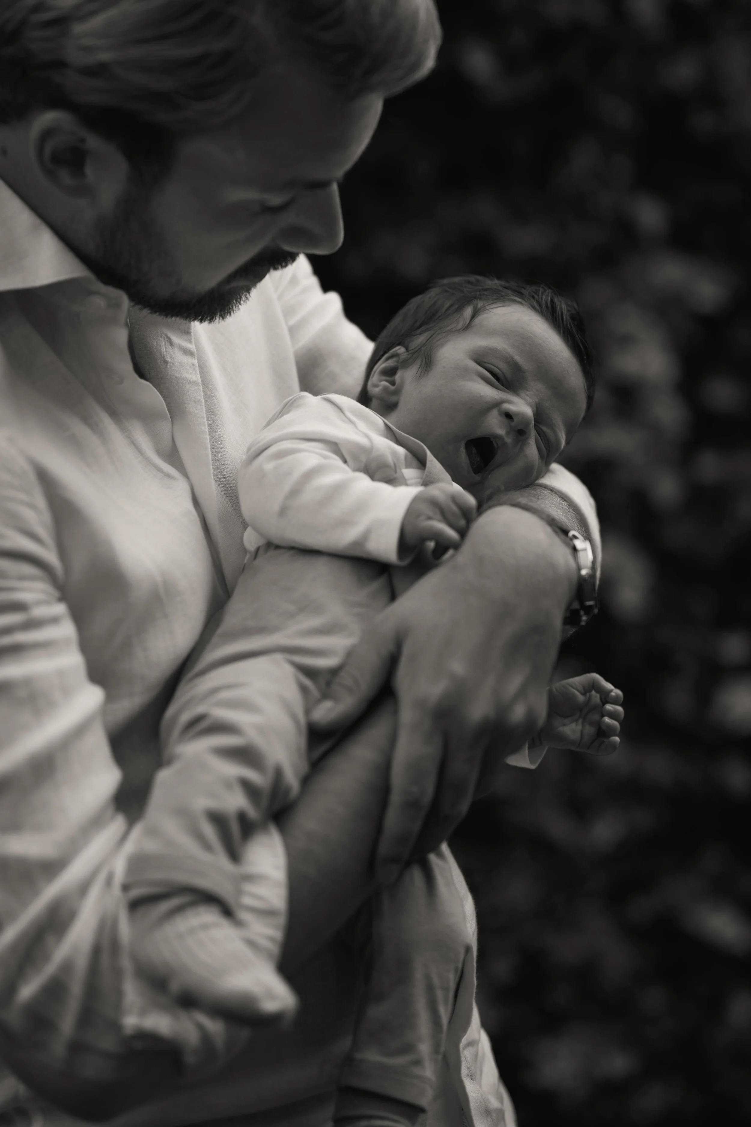 A man holding a laughing baby in black and white.