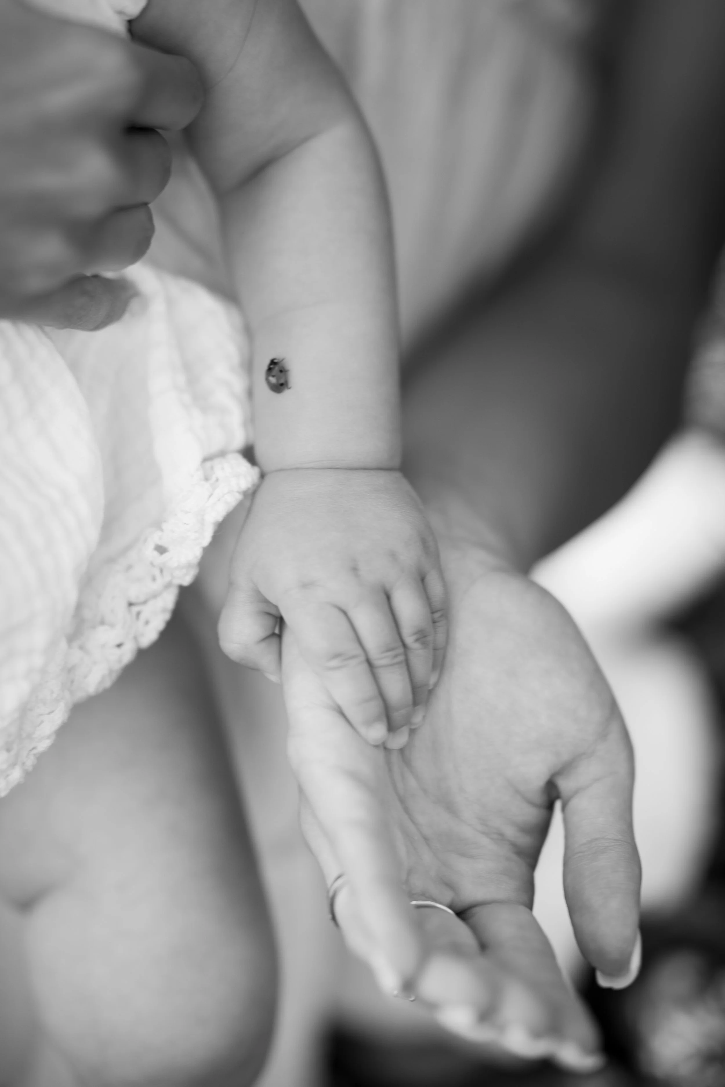 Close-up black and white photo of a baby's hand gripping an adult's finger.