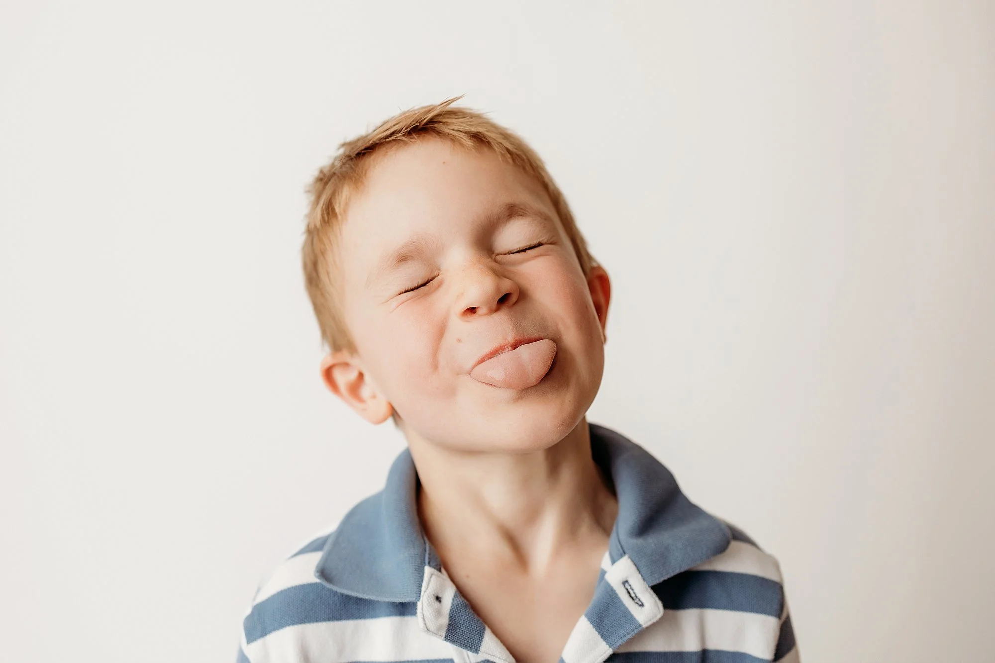 Child laughing naturally during a personality portrait session on a clean white backdrop in an Indiana photography studio