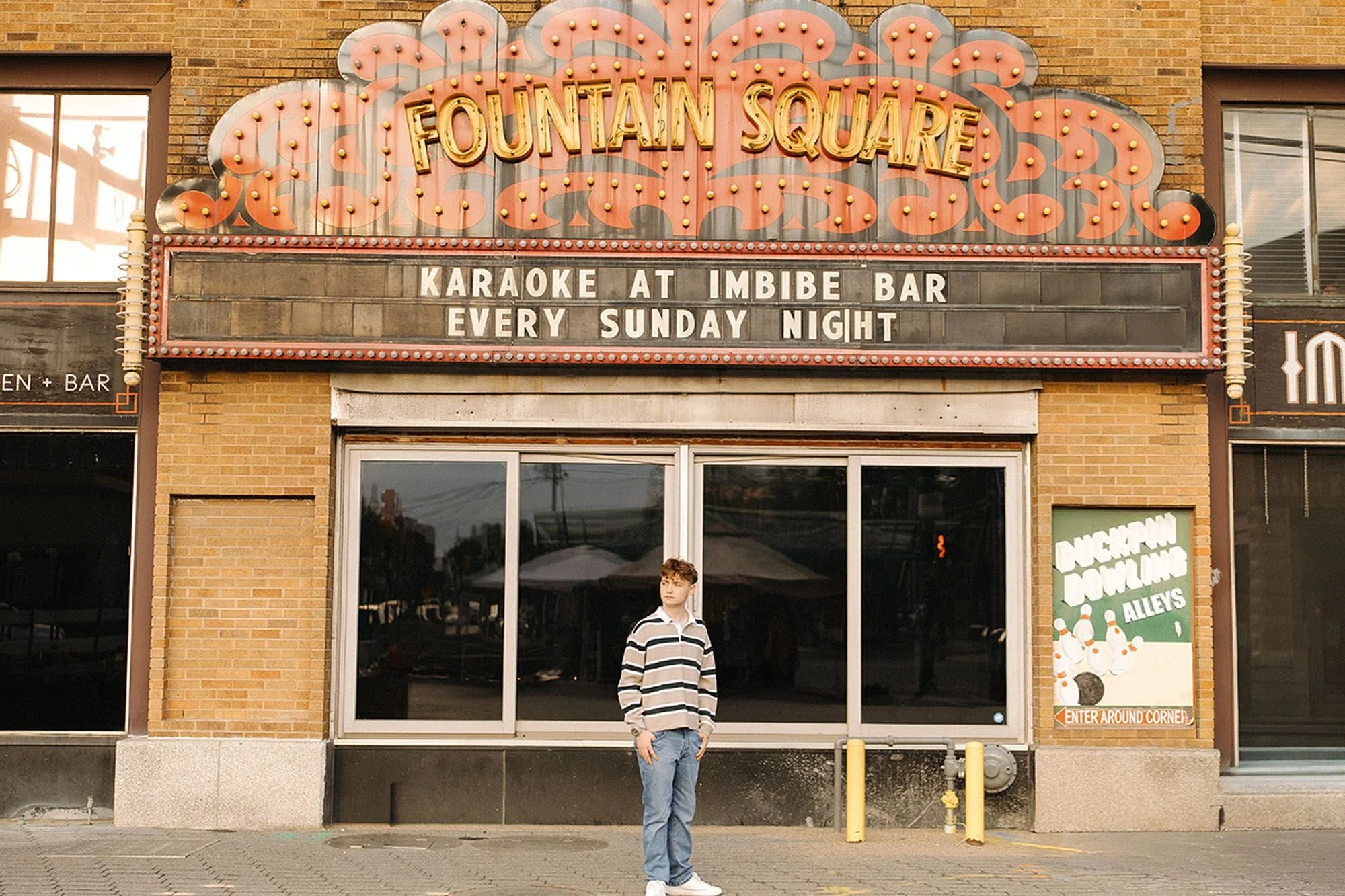 Senior standing beneath the iconic Fountain Square marquee in downtown Sheridan, Wyoming during a modern urban senior photo session