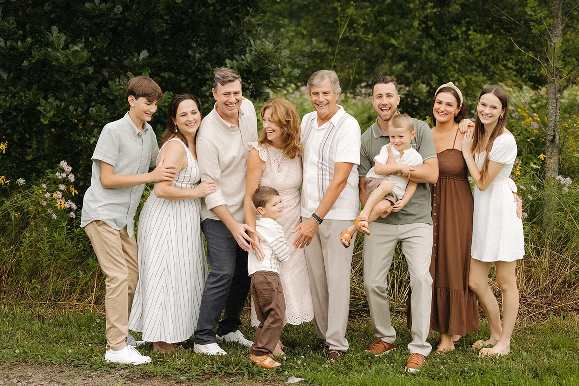 Three generations of an extended family gathered together in a wildflower field during a summer family photo session at MacGregor Park in Westfield, Indiana.
