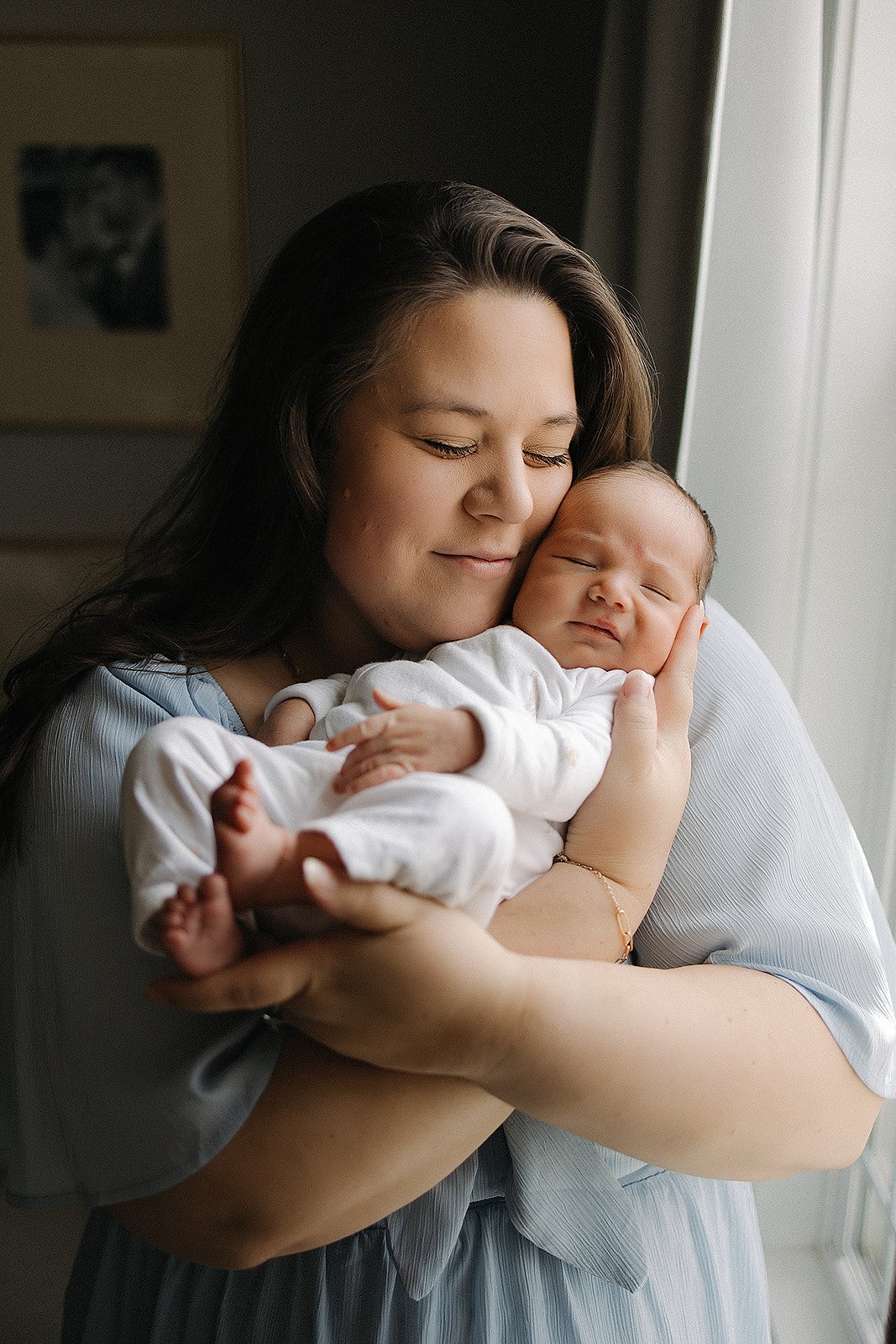 Newborn photography Indianapolis with mother holding baby by window at home