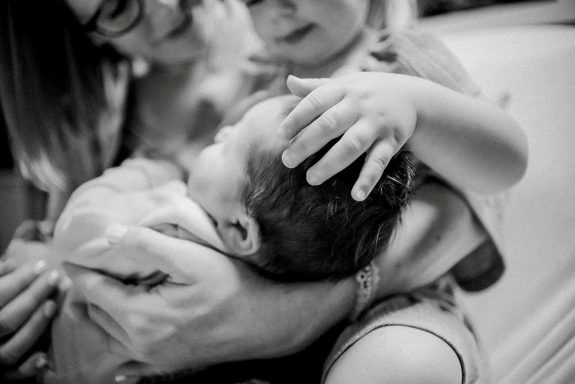 A Mother and her child hold a newborn baby, showcasing a loving family moment in a hospital environment