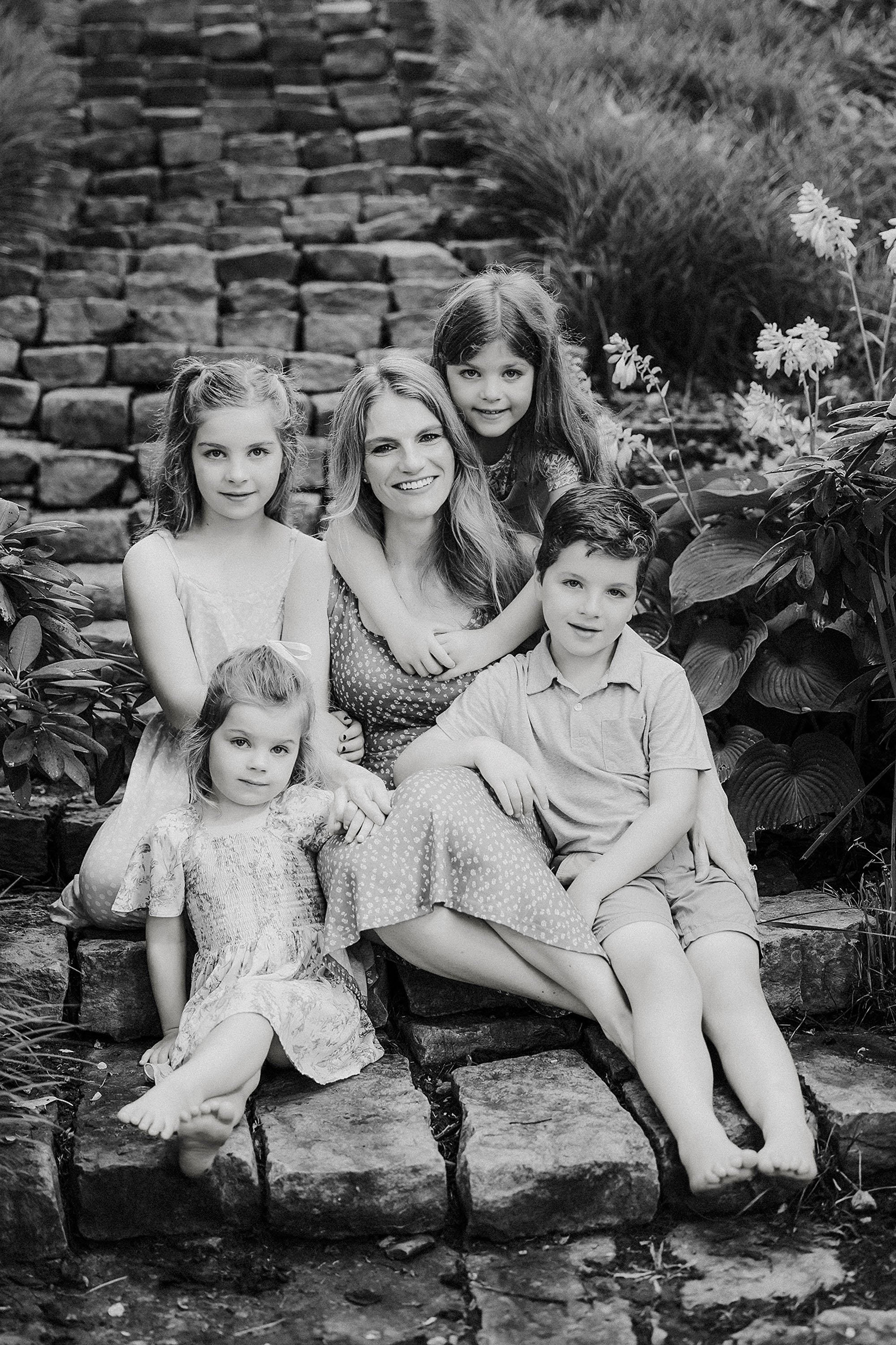  black and white photo of 5 children hugging their mother on the back yard stone steps of their home during documentary photos with lauren lewis, the heart narrative   