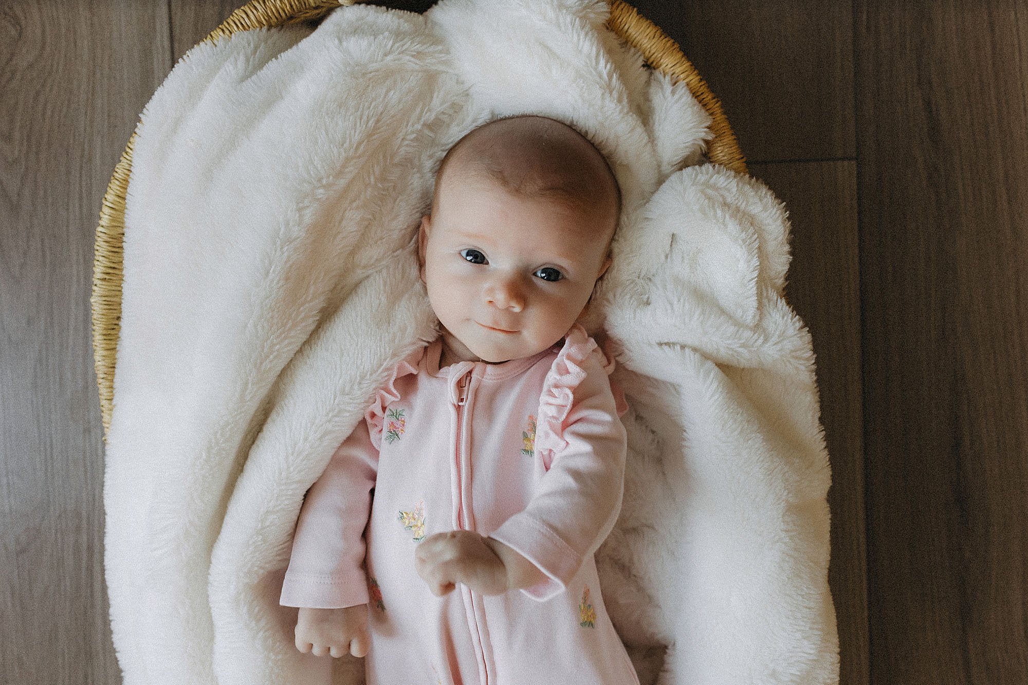  newborn baby smiling in basket during lifestyle newborn photography session 