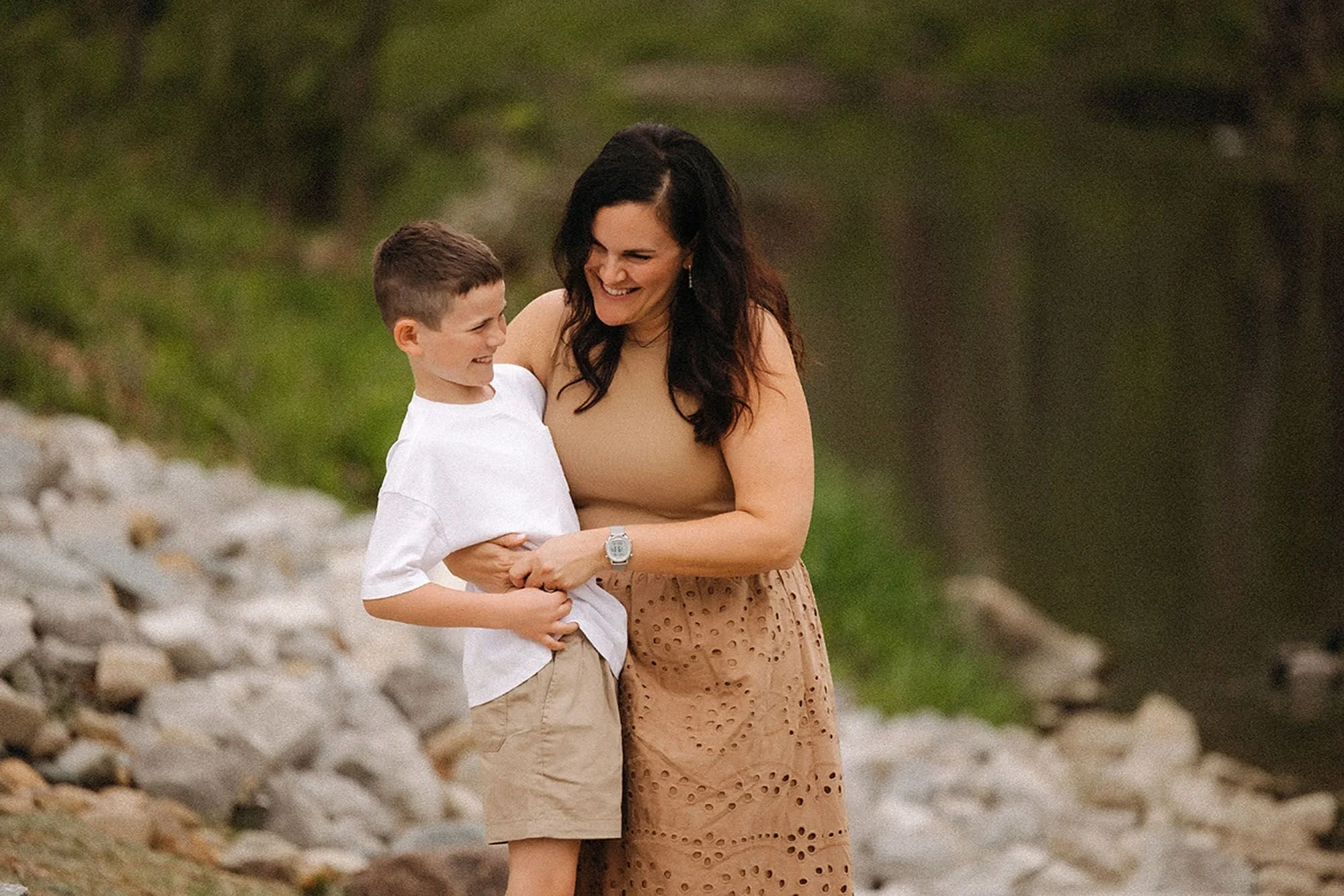 Mother laughing with her son during an outdoor portrait session, showing how to prepare kids for family photos with playful moments and genuine smiles