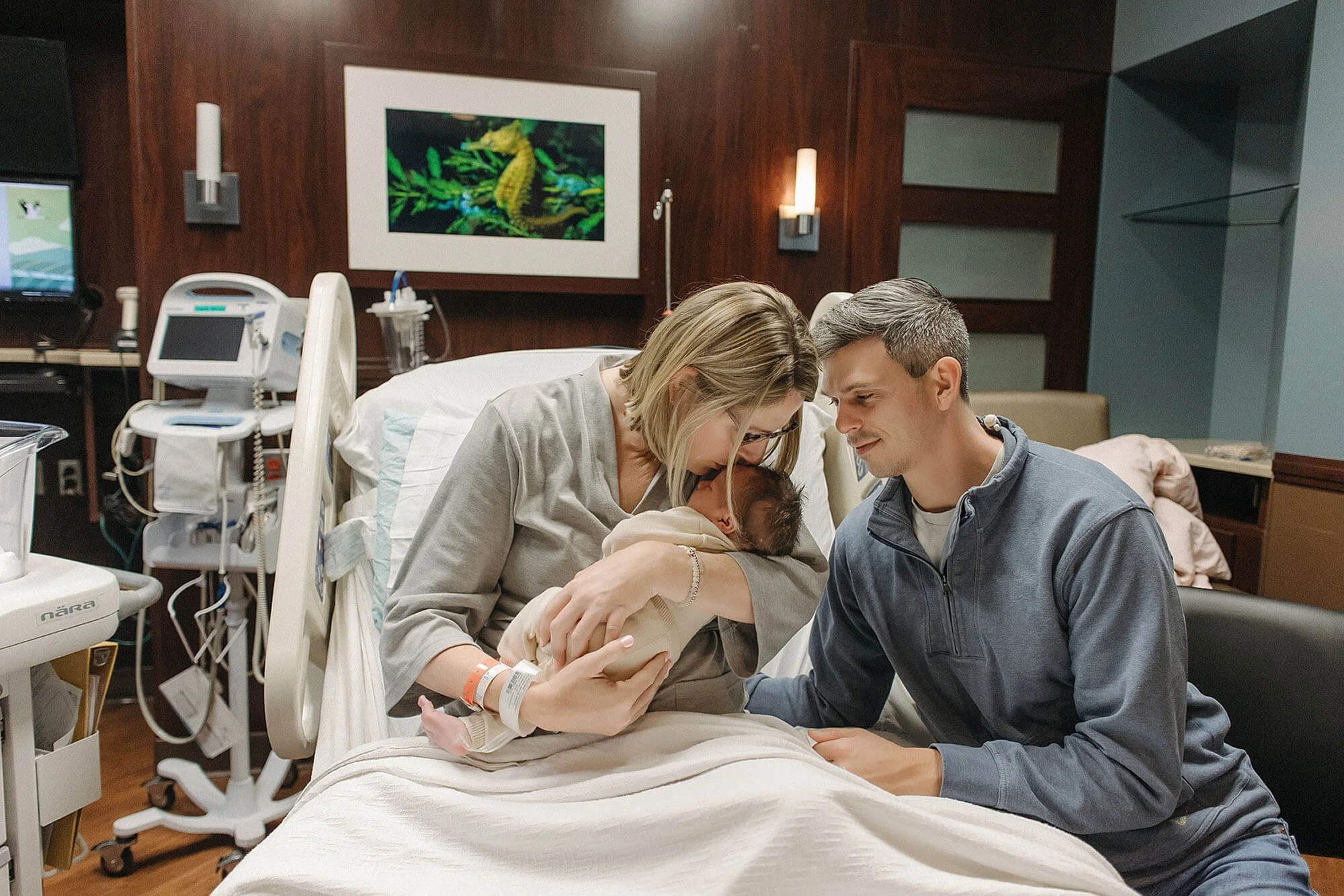 A couple holds their newborn baby, highlighting a precious moment from a Fresh 48 newborn photo sessio