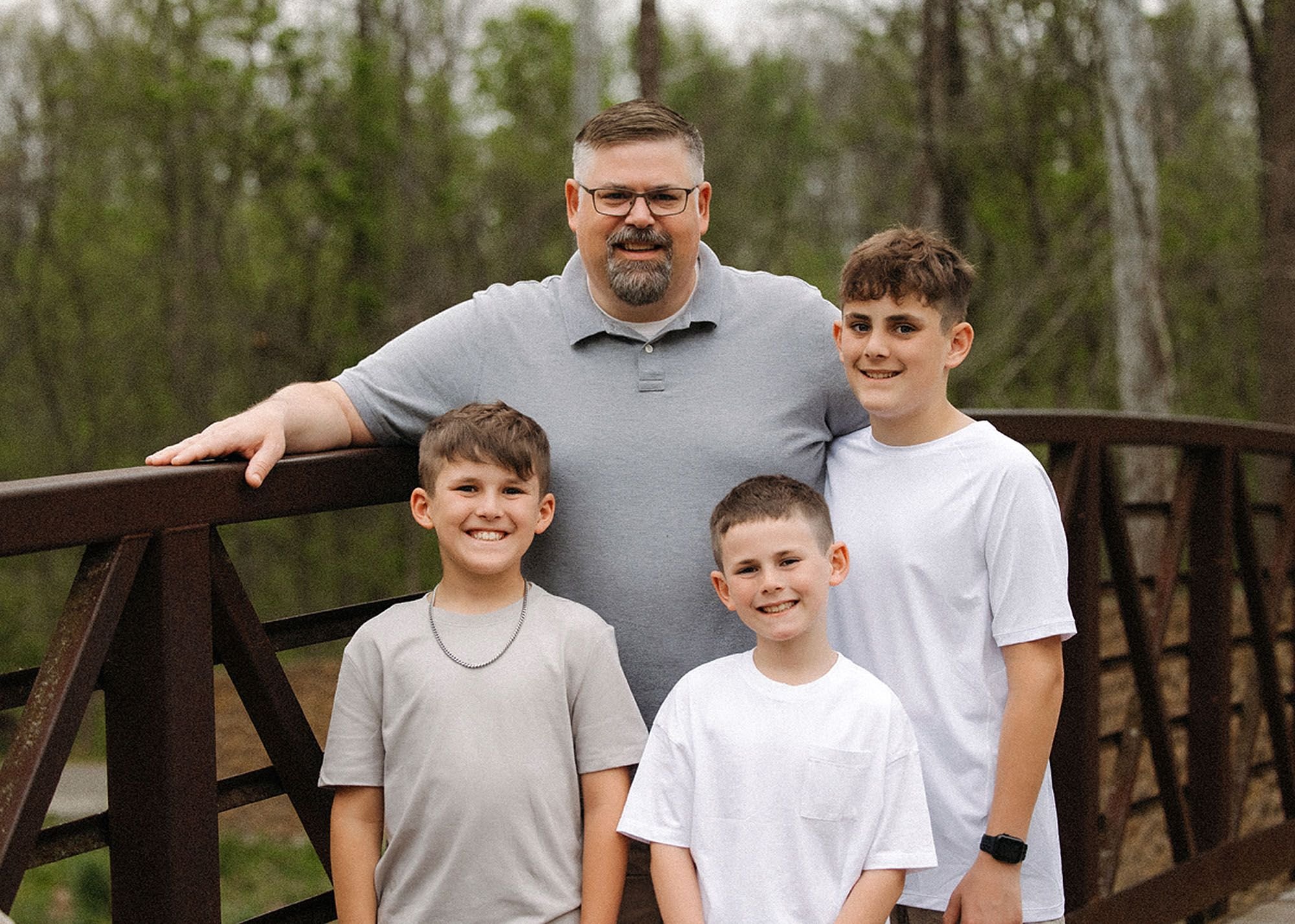 Happy father and three boys enjoying an outdoor portrait session, demonstrating tips to prepare kids for family photos without stress