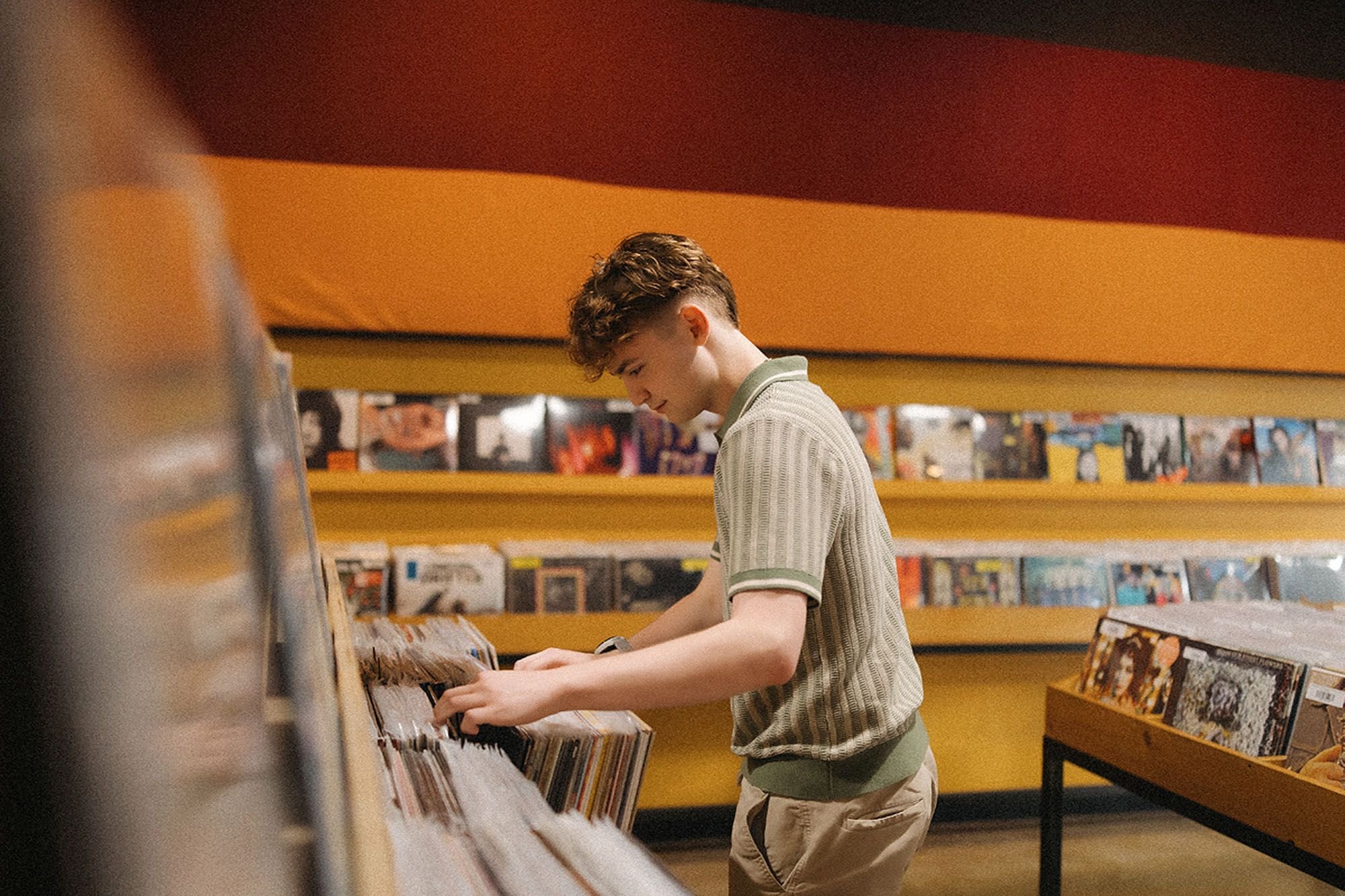 A man browses vinyl records in a record store at Fountain Square, Indianapolis, surrounded by colorful album covers