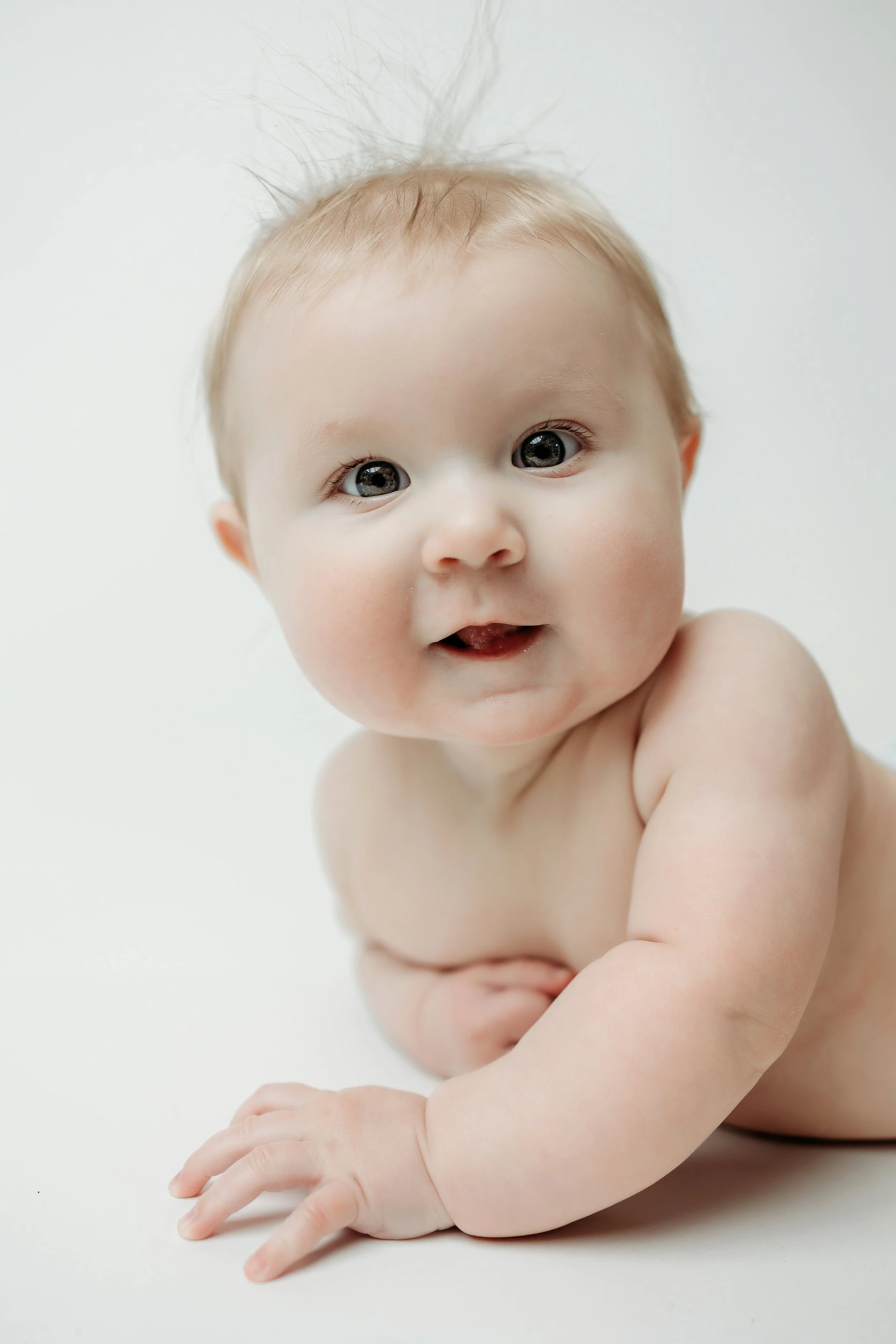 baby smiling and looking up at the camera, celebrating their 6-month milestone