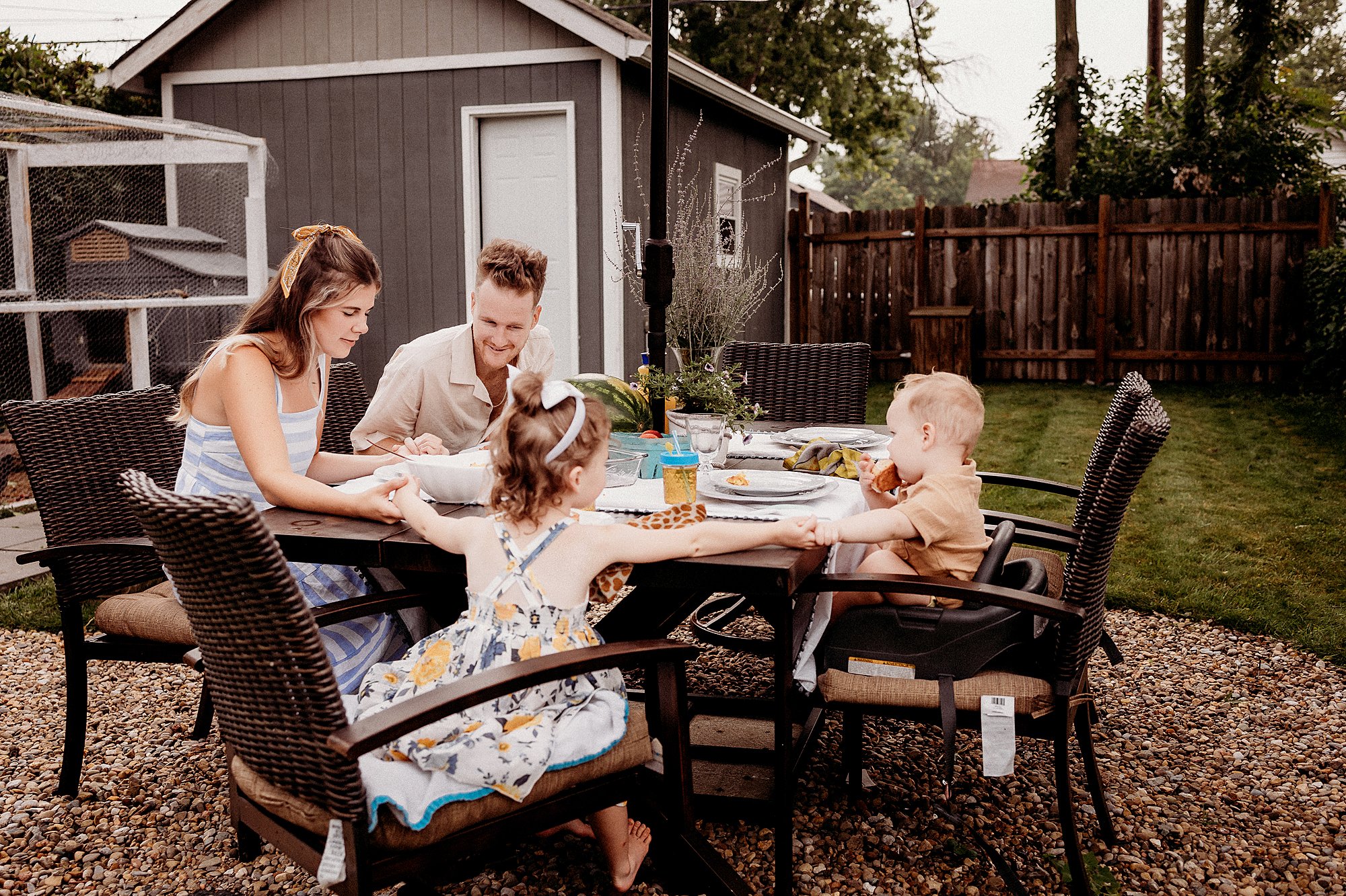 A family seated at a table outside, captured during a backyard photography session in Indianapolis, Indiana