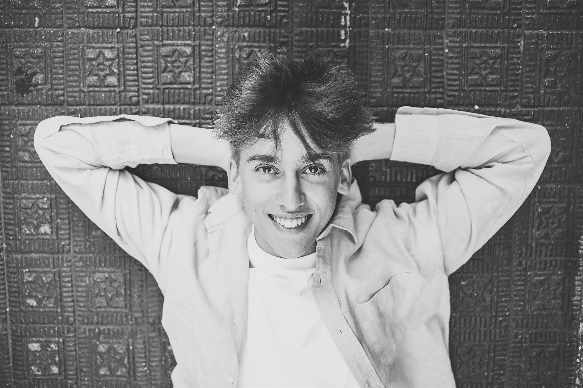 A man smiles while posing for a photo in downtown Noblesville, showcasing his excitement for his senior portraits
