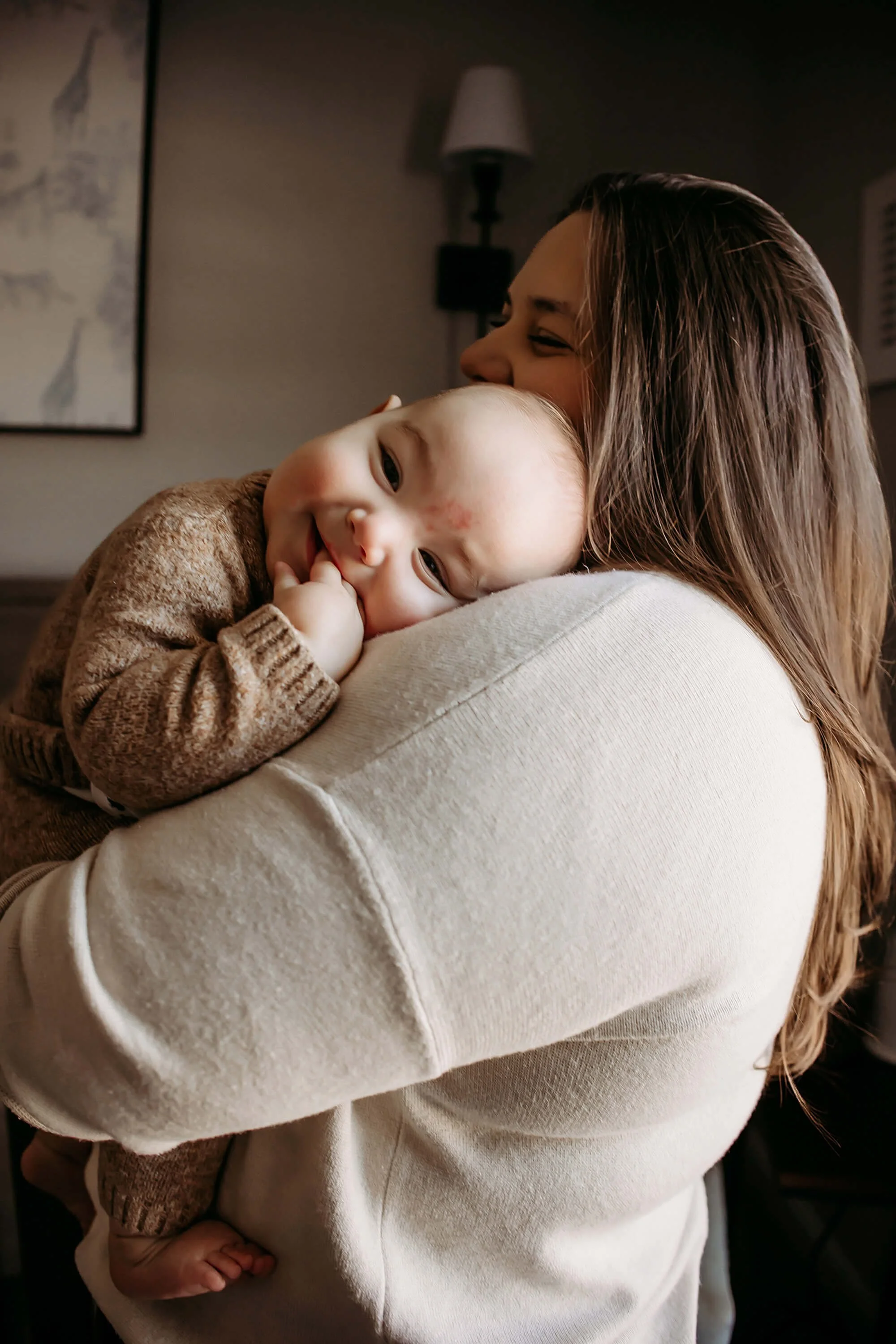 6 month baby snuggles mothers shoulder at home during milestone photoshoot documenting his first year