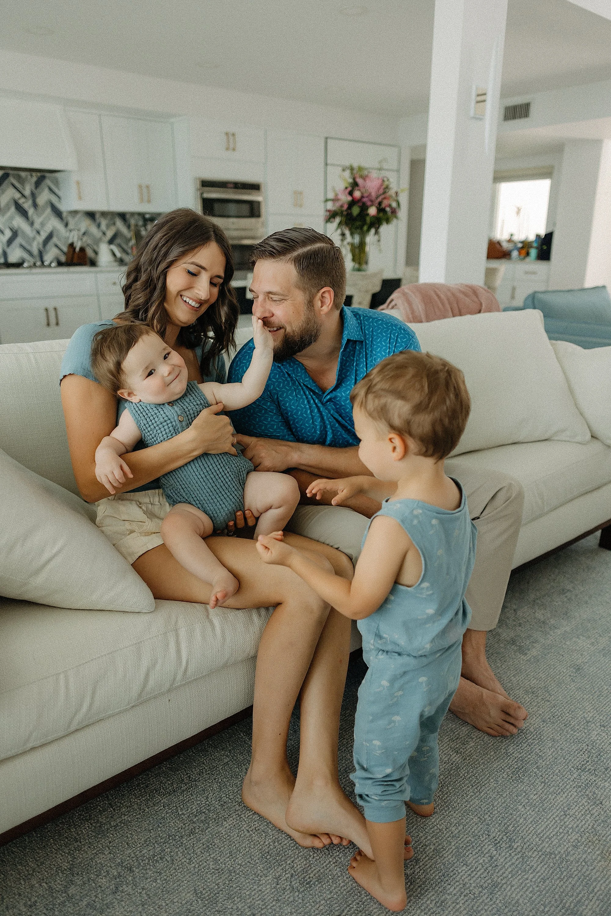 Parents sitting on couch with their two young sons during an at-home lifestyle family photography session.