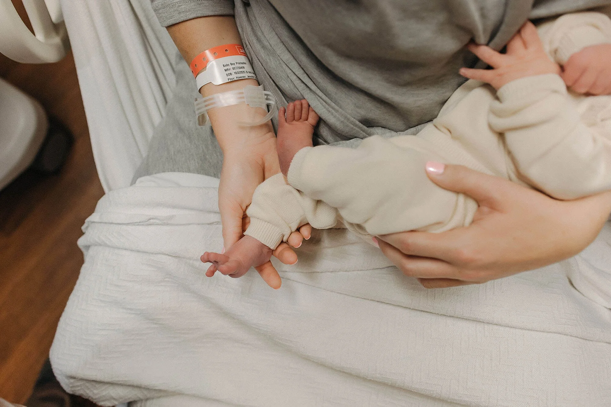 A mother holds her baby in a hospital bed, showcasing a heartfelt moment from a Fresh 48 newborn photo session