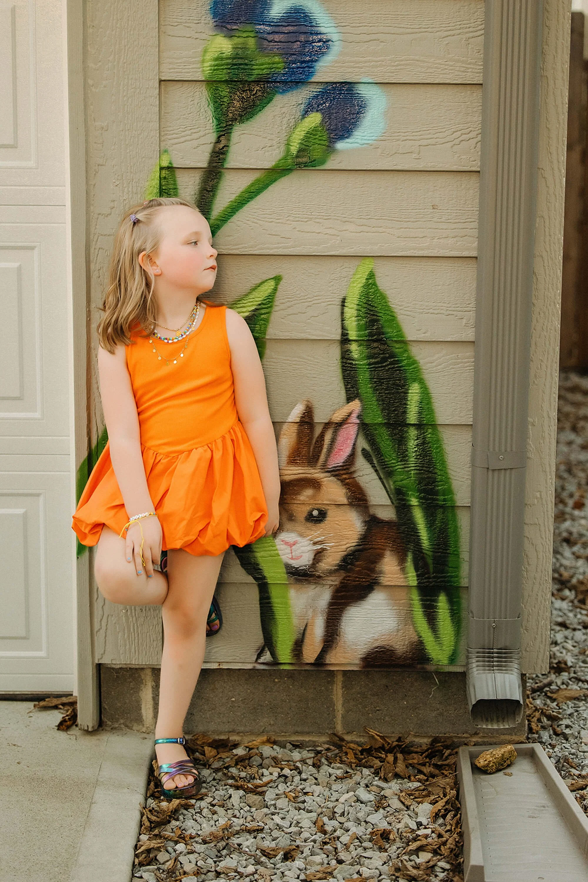 Kindergarten aged sister in neon orange poses in front of flower graffiti in flower alley, the broadripple area of indianapolis
