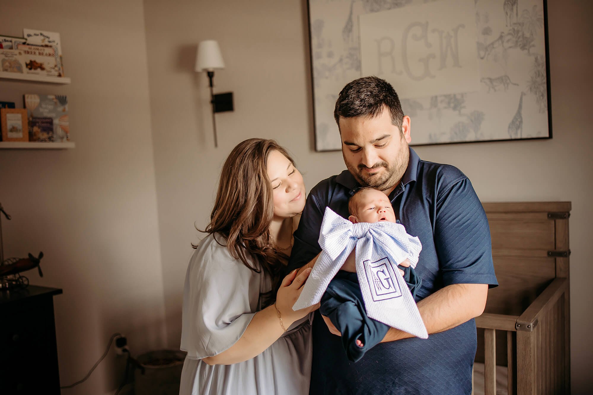 documenting babys first year during in home newborn photos in westfield with theheart narrative- mom dad and infant hold each other in nursery