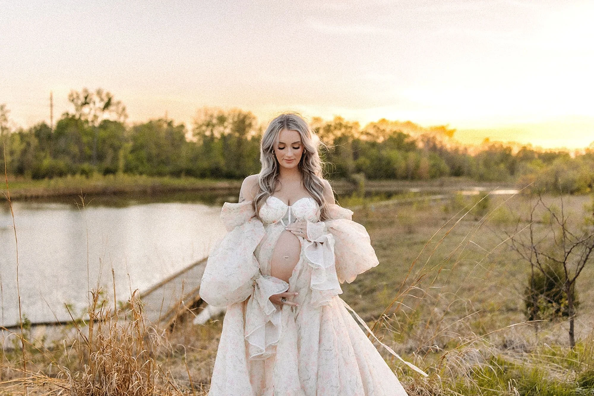 Expectant mother in a flowing white gown beside a peaceful lake at sunset—timeless Maternity Photos in Central Indiana