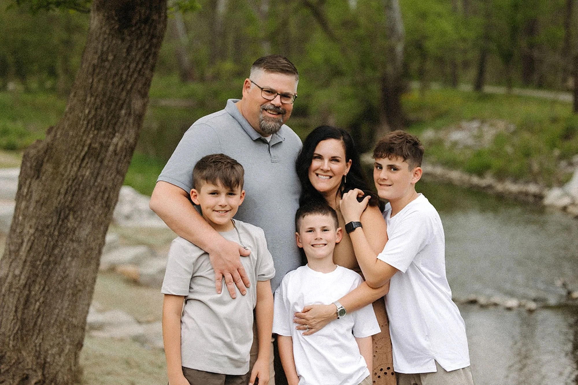 Happy family smiling together outdoors, showing how to prepare kids for family photos with a relaxed and stress-free approach