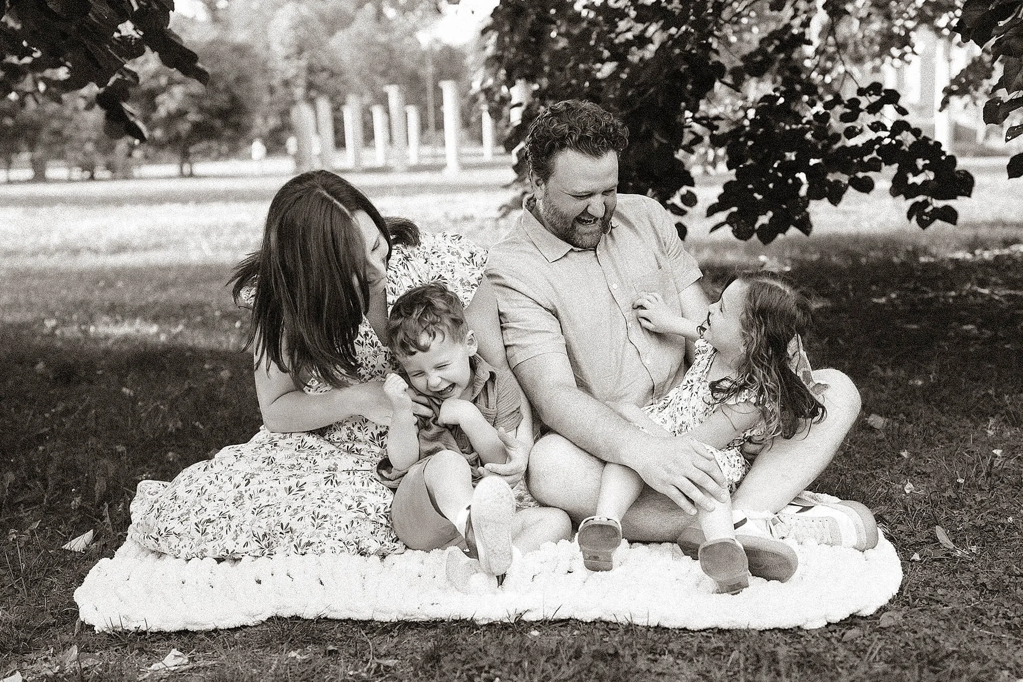 Parents cuddling their children during an outdoor mini photography session.
