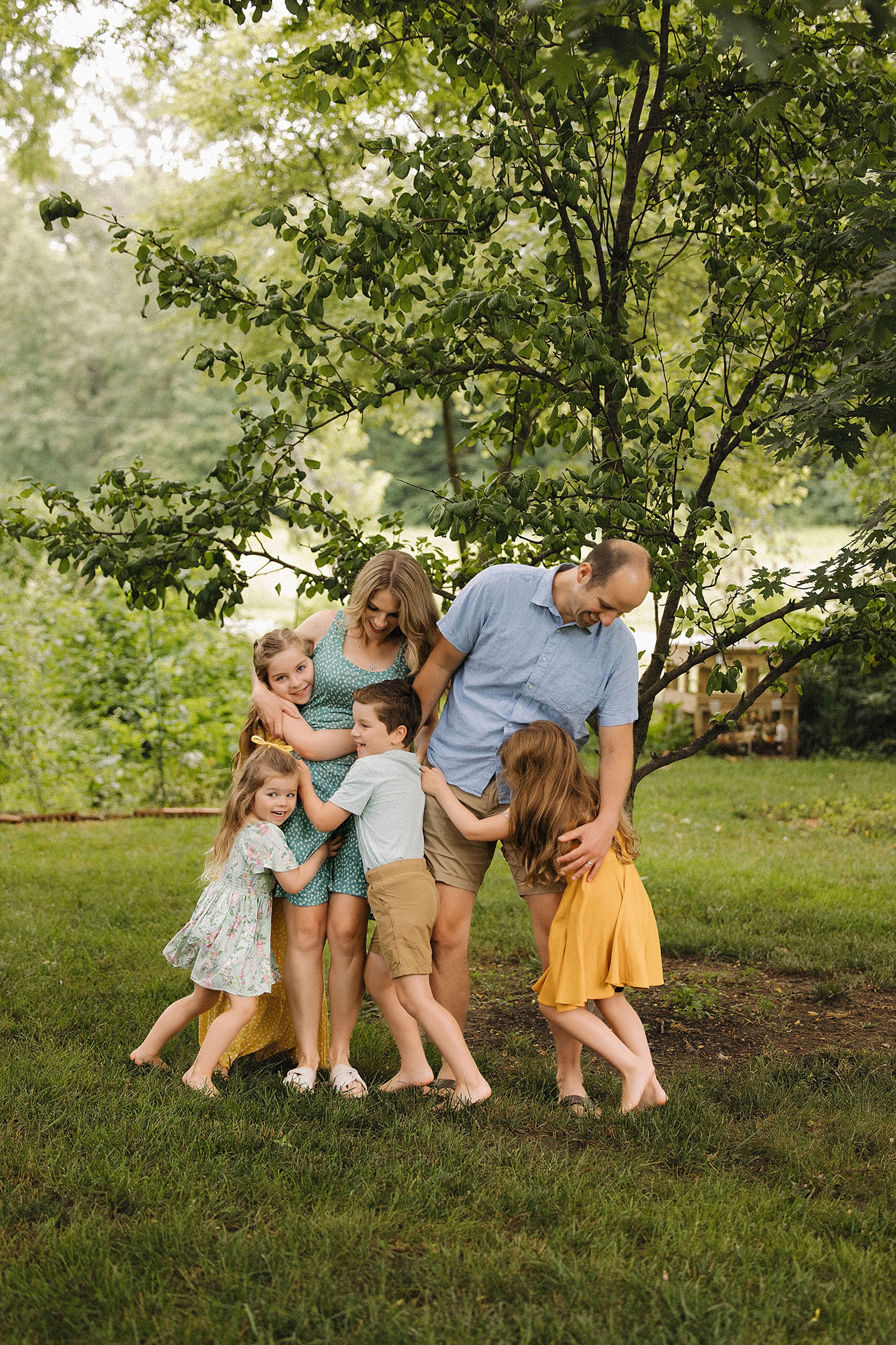 Parents hugging their kids in the backyard during a relaxed at-home family session in Indianapolis.