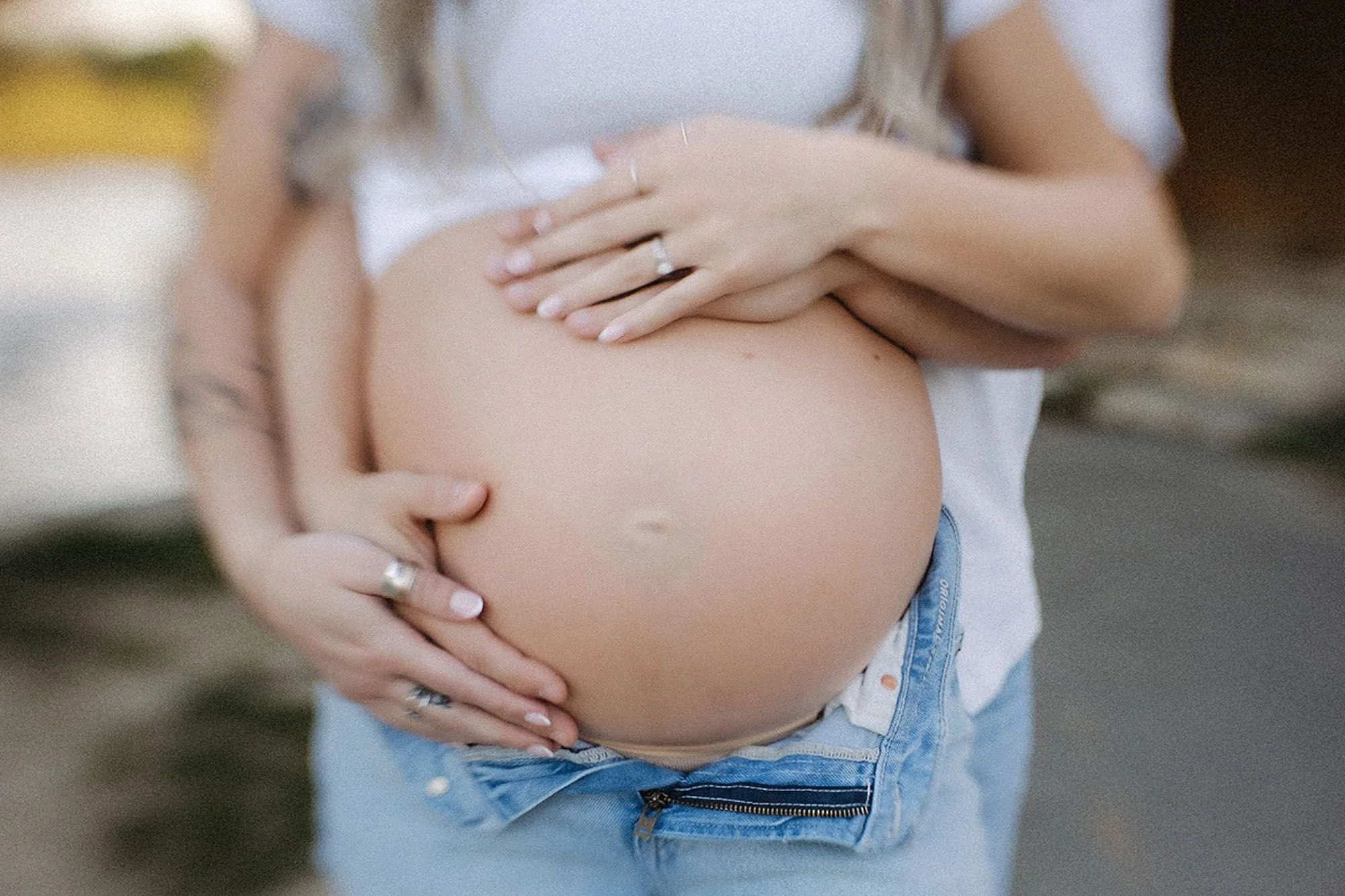 Close-up of an expectant mother gently cradling her baby bump in natural maternity photos outdoors in Central Indiana