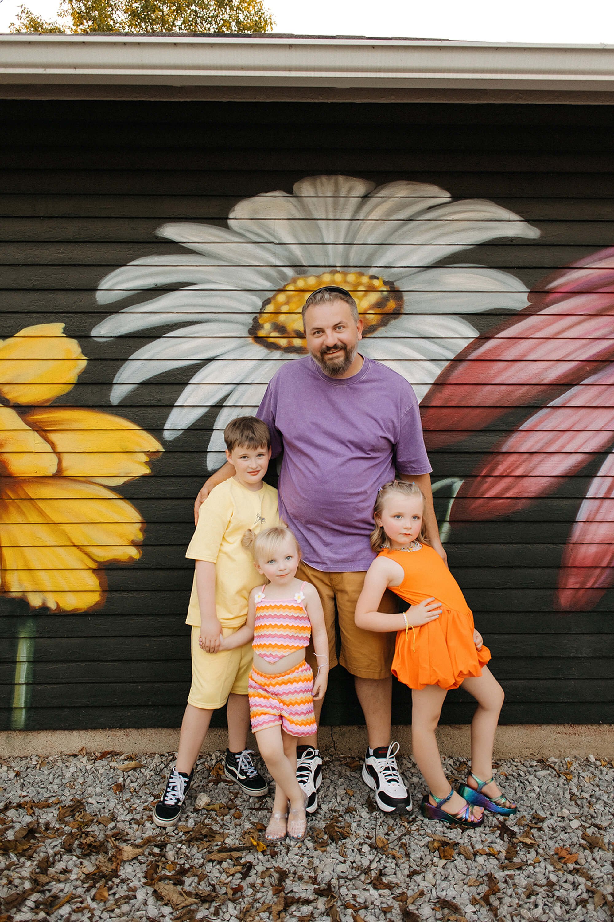  portrait of dad and kids wearing vibrant colors during broadripple’s flower alley in indianpapolis 