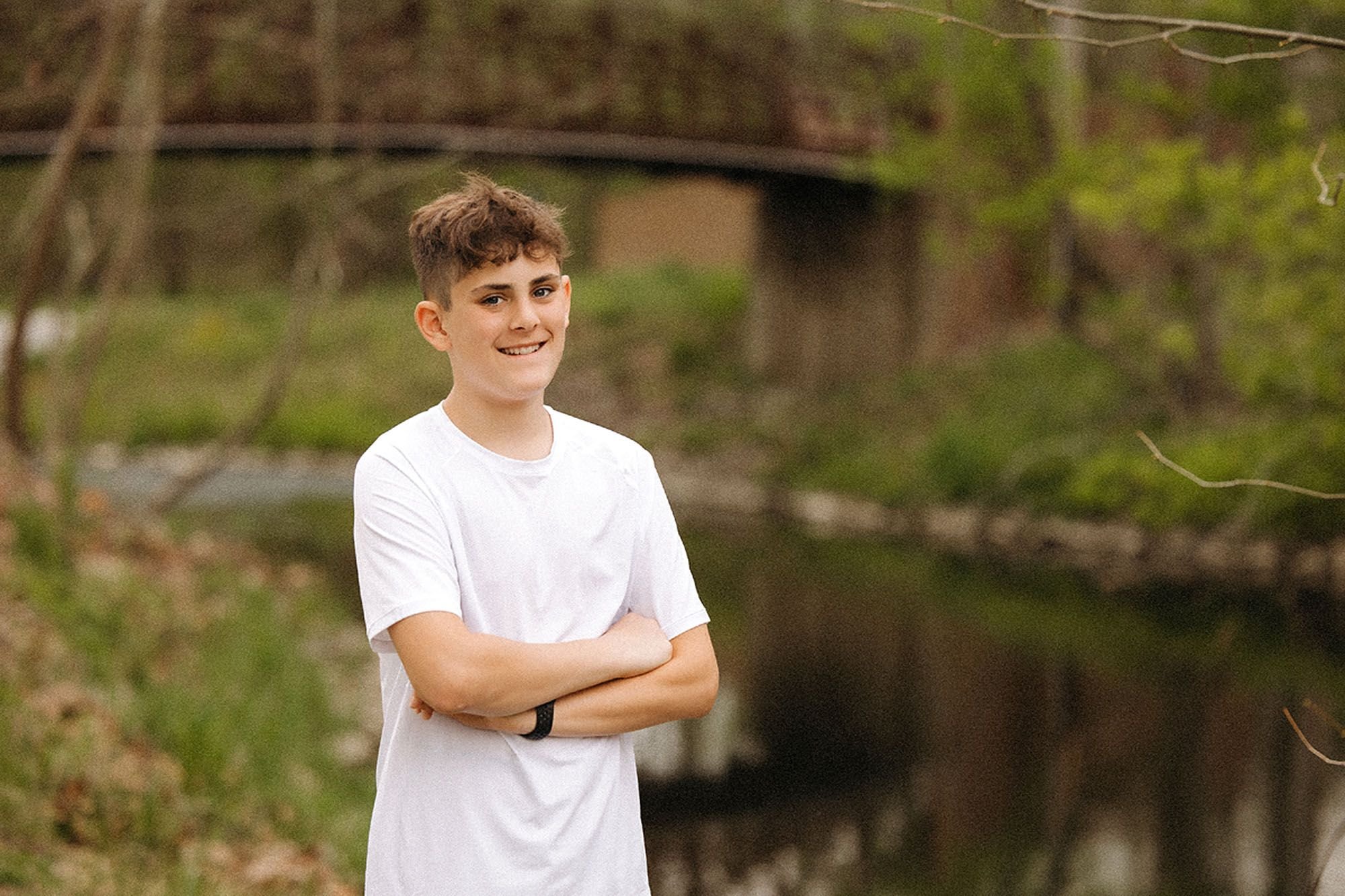 Confident teenage boy posing during an outdoor family photo session, showing how to prepare kids for family photos with ease and genuine smiles