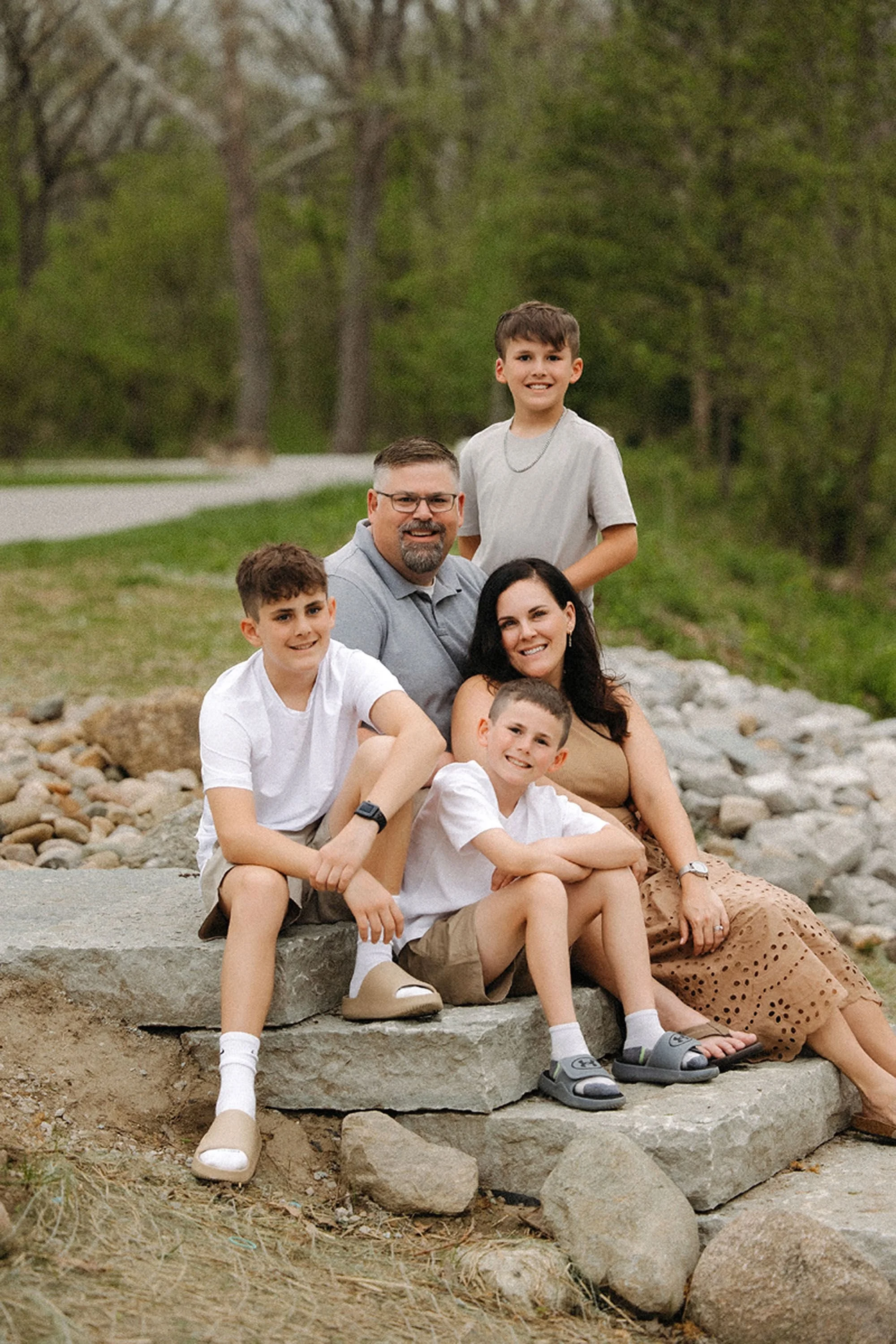 Family of five smiling together during an outdoor portrait session, showing how to prepare kids for family photos with a relaxed and joyful atmosphere