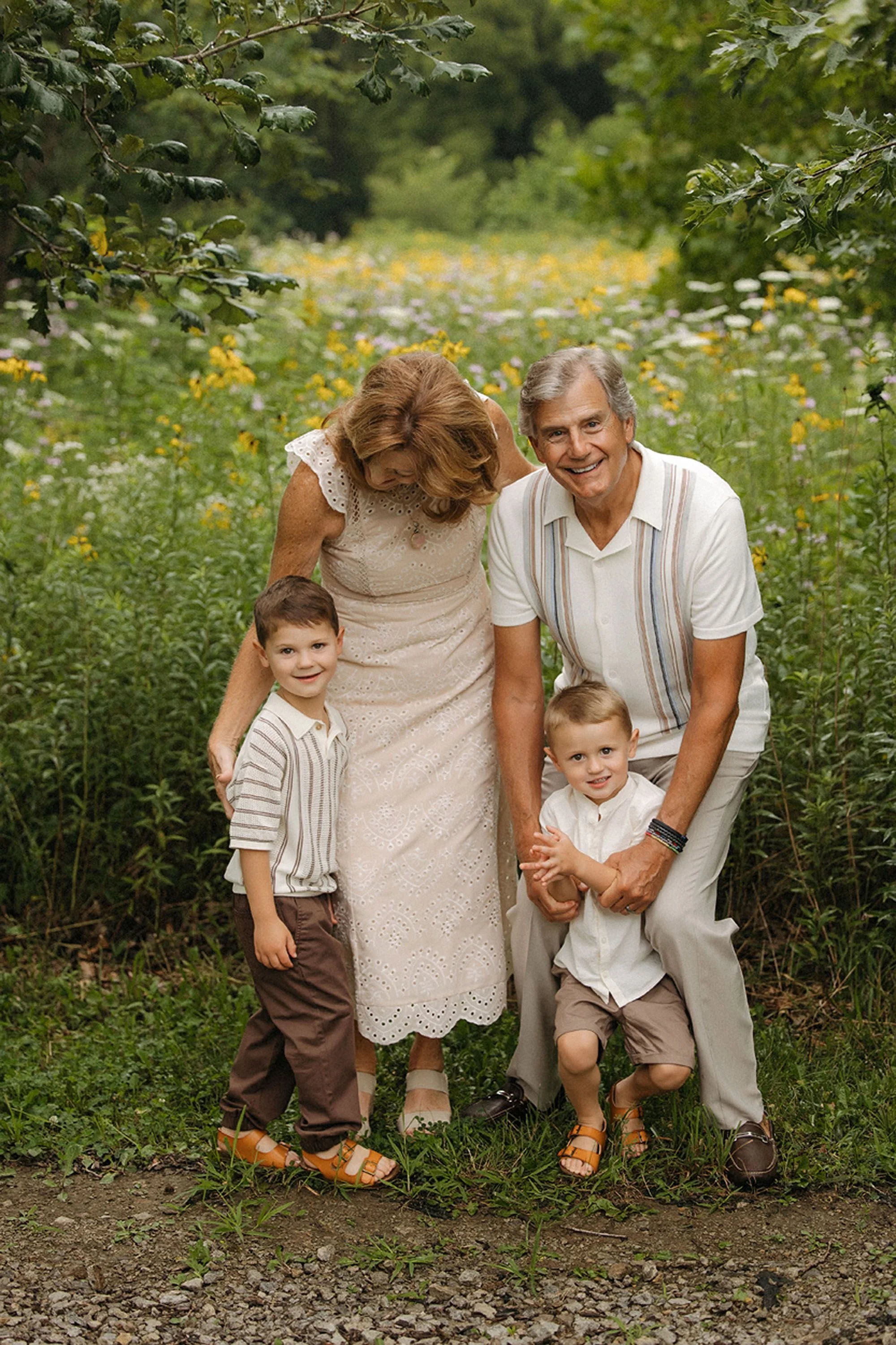 Grandparents laughing and playing with their young grandsons in a wildflower field during a family session.