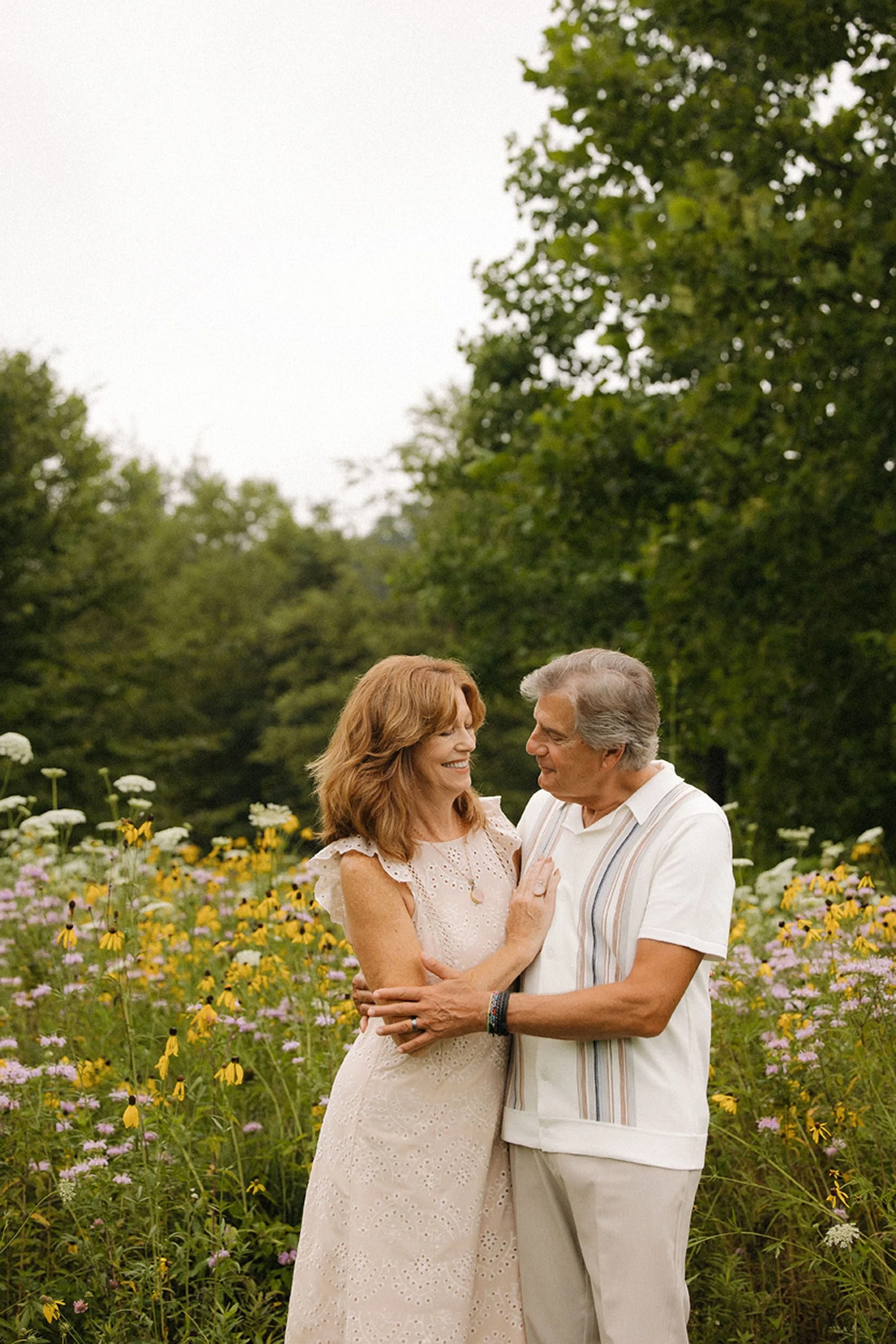 Grandparents embracing each other in a wildflower field during a summer photo session.