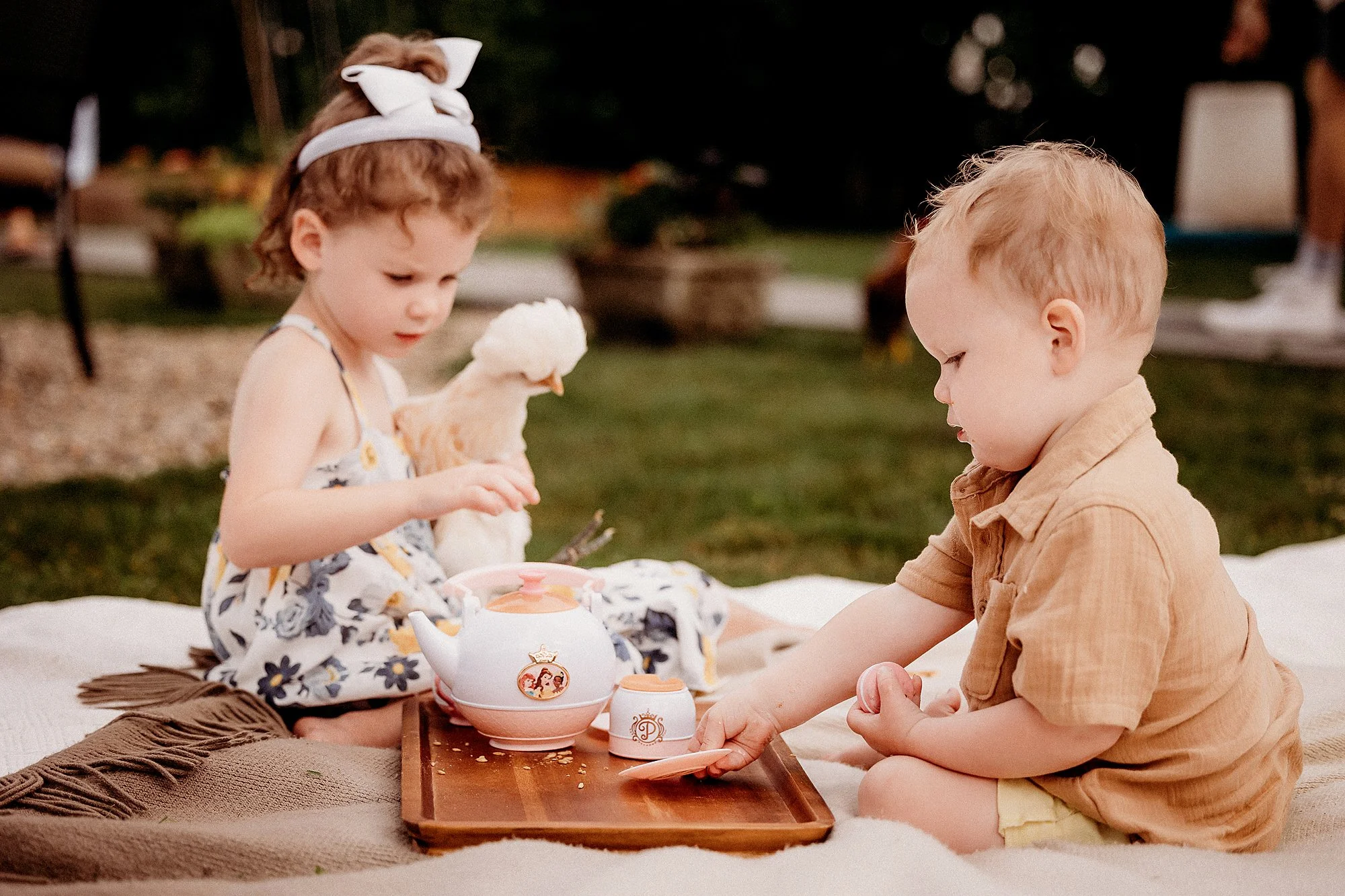 A photography session captures two children enjoying a tea set on a blanket in Indianapolis, Indiana