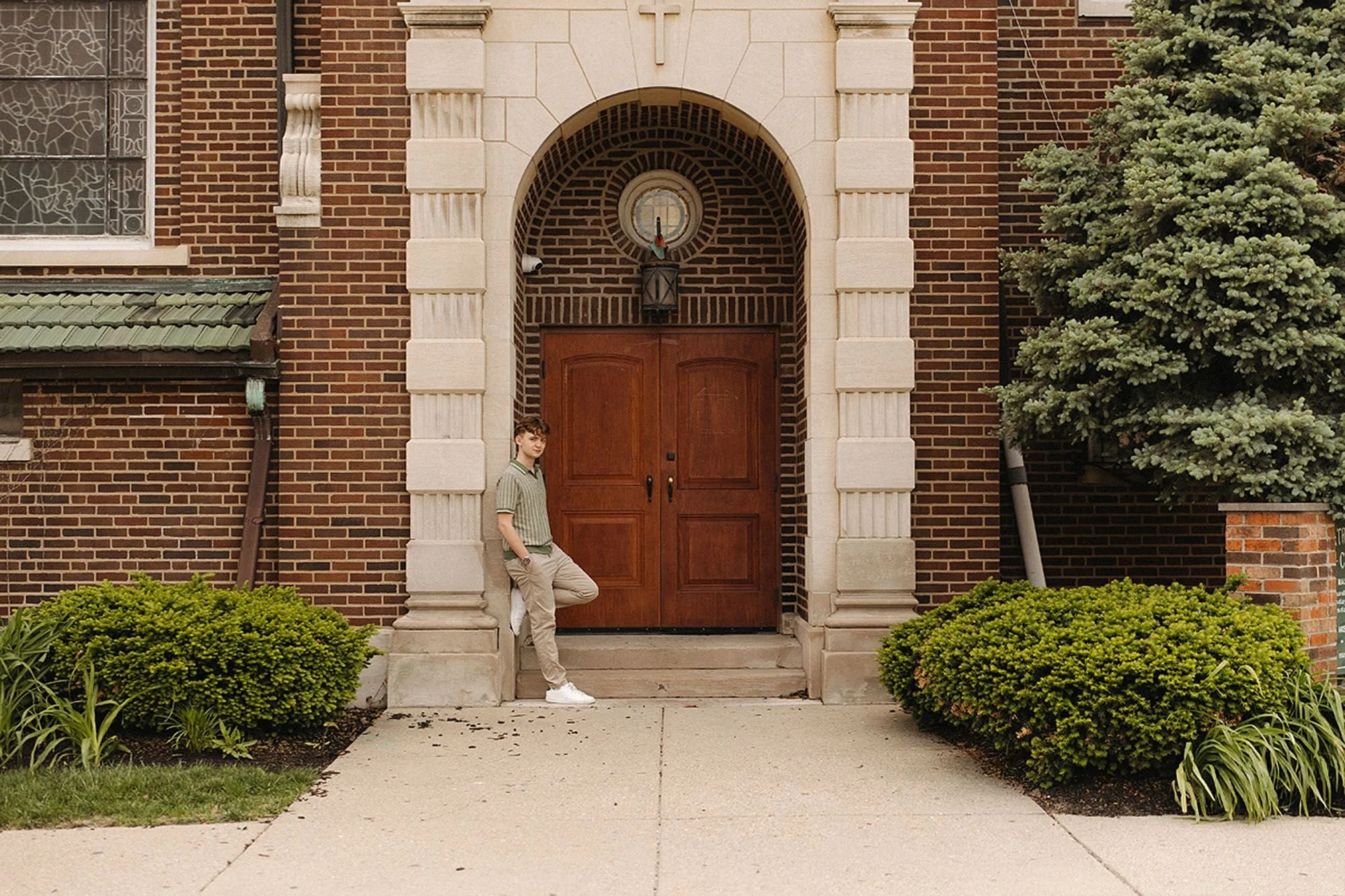 Senior photo of a man standing in front of a church door, with Fountain Square, Indianapolis, as the backdrop