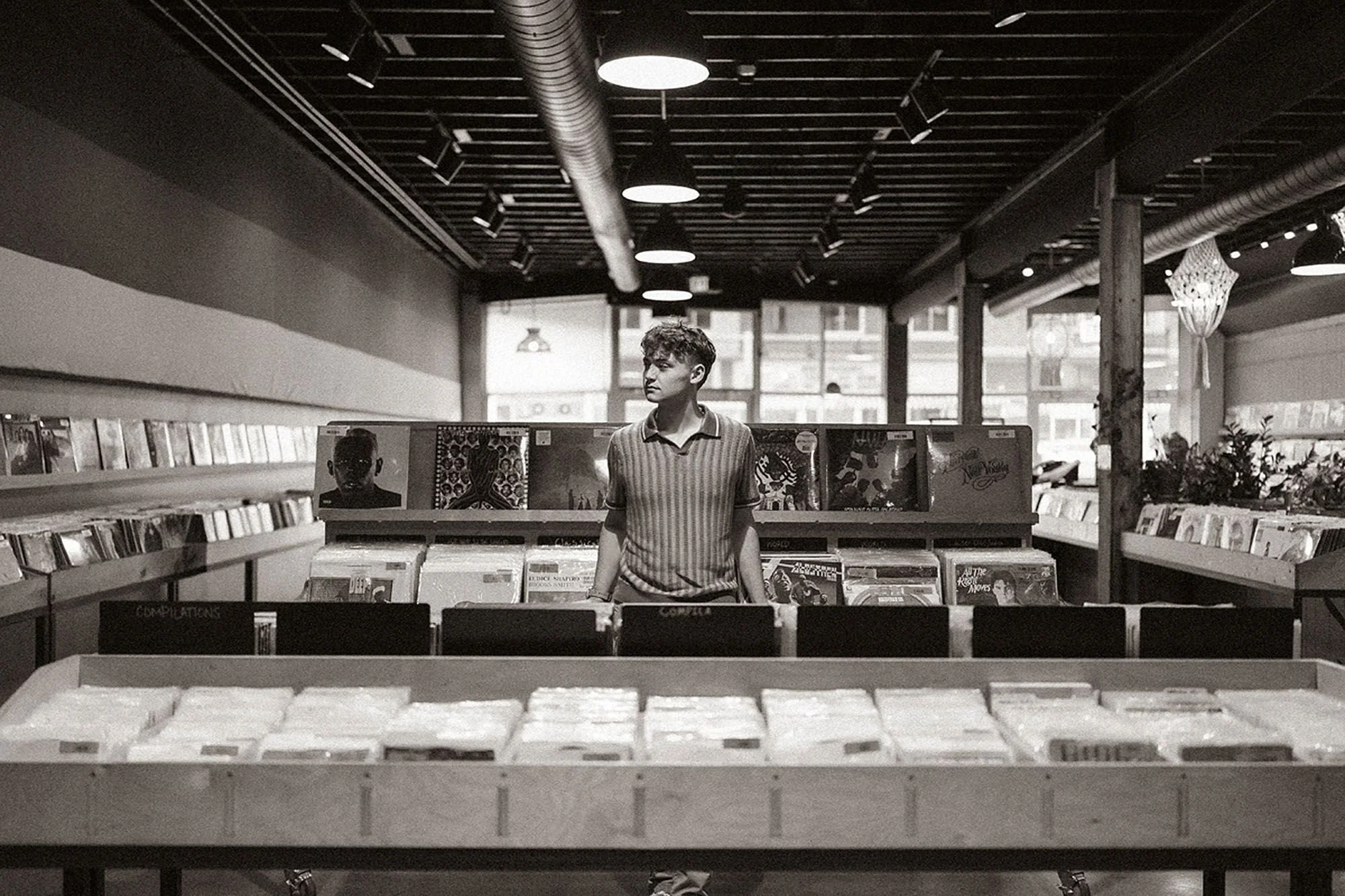 Senior photo of a man standing outside a record store in Fountain Square, Indianapolis, with vibrant storefront details